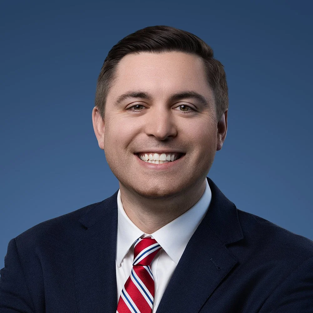 Jack Russell, President & CEO of OneZone Chamber, smiling in a navy suit and red striped tie, professional headshot