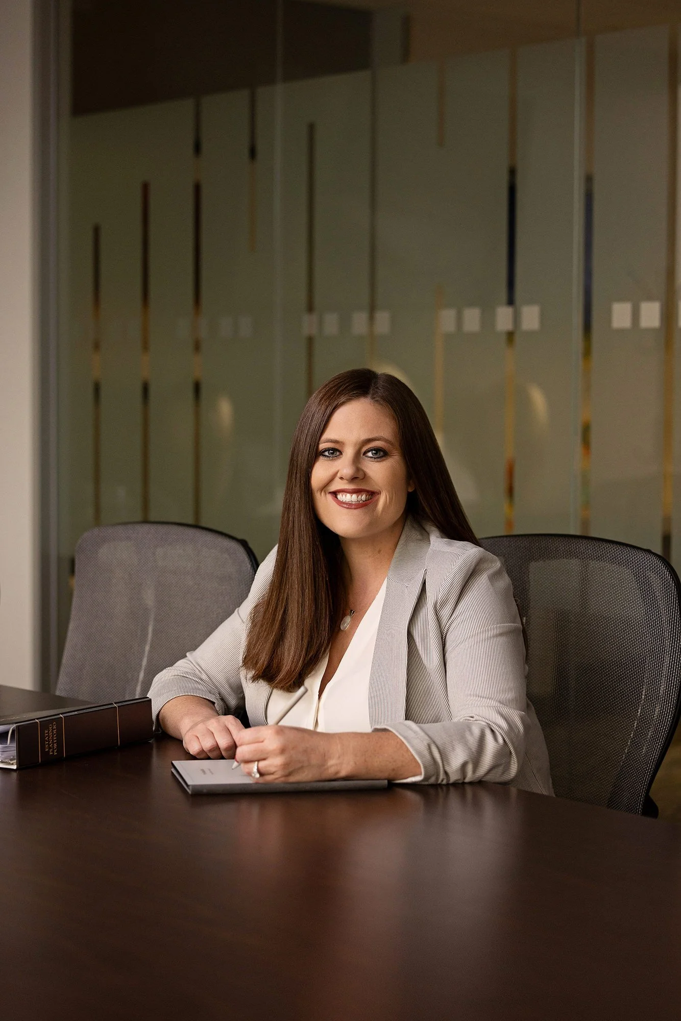 Smiling attorney in a white blazer seated at a conference table, professional branding portrait in Fishers, IN