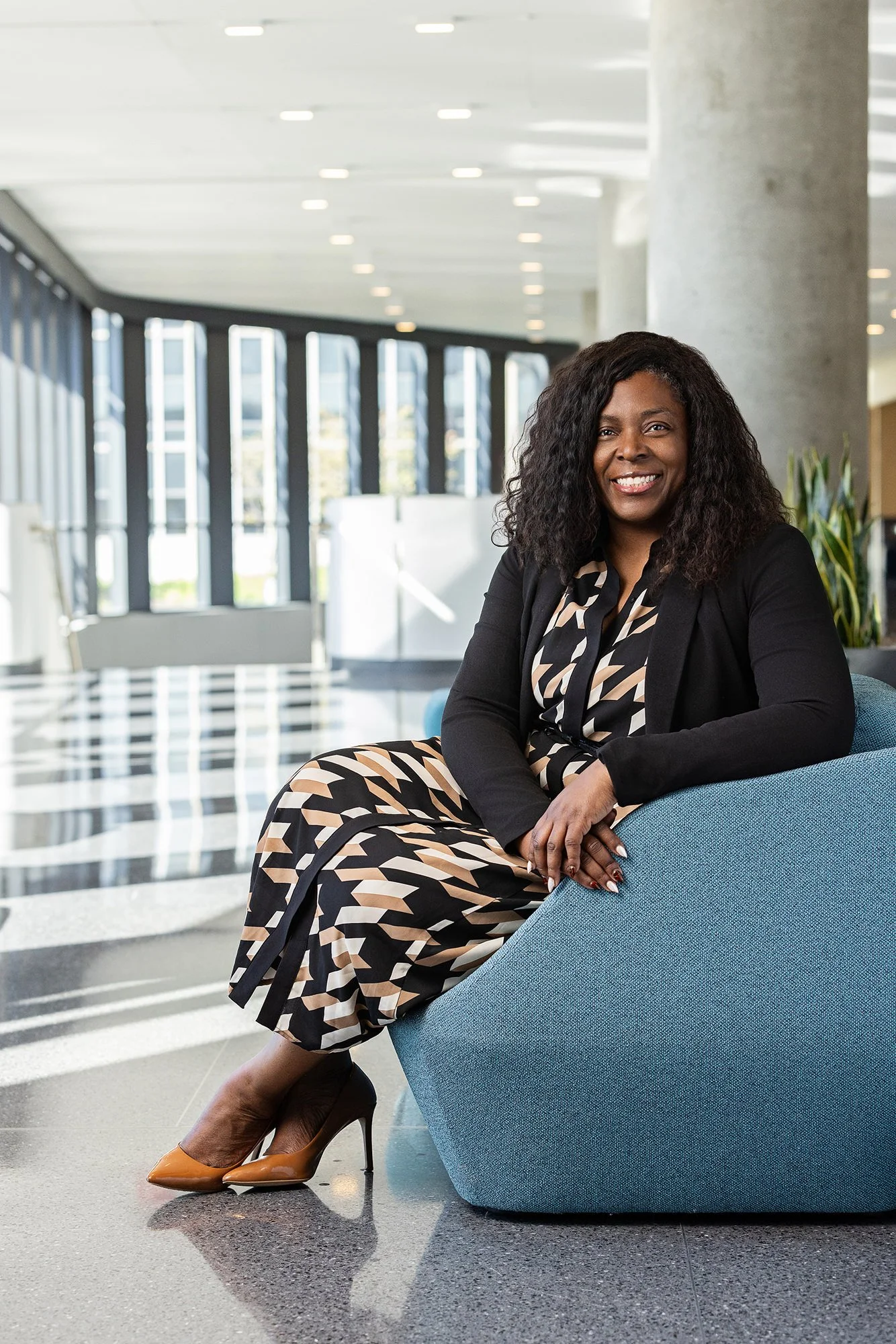 Woman in a patterned dress seated in a sunlit atrium, Cummins corporate portrait in Indianapolis