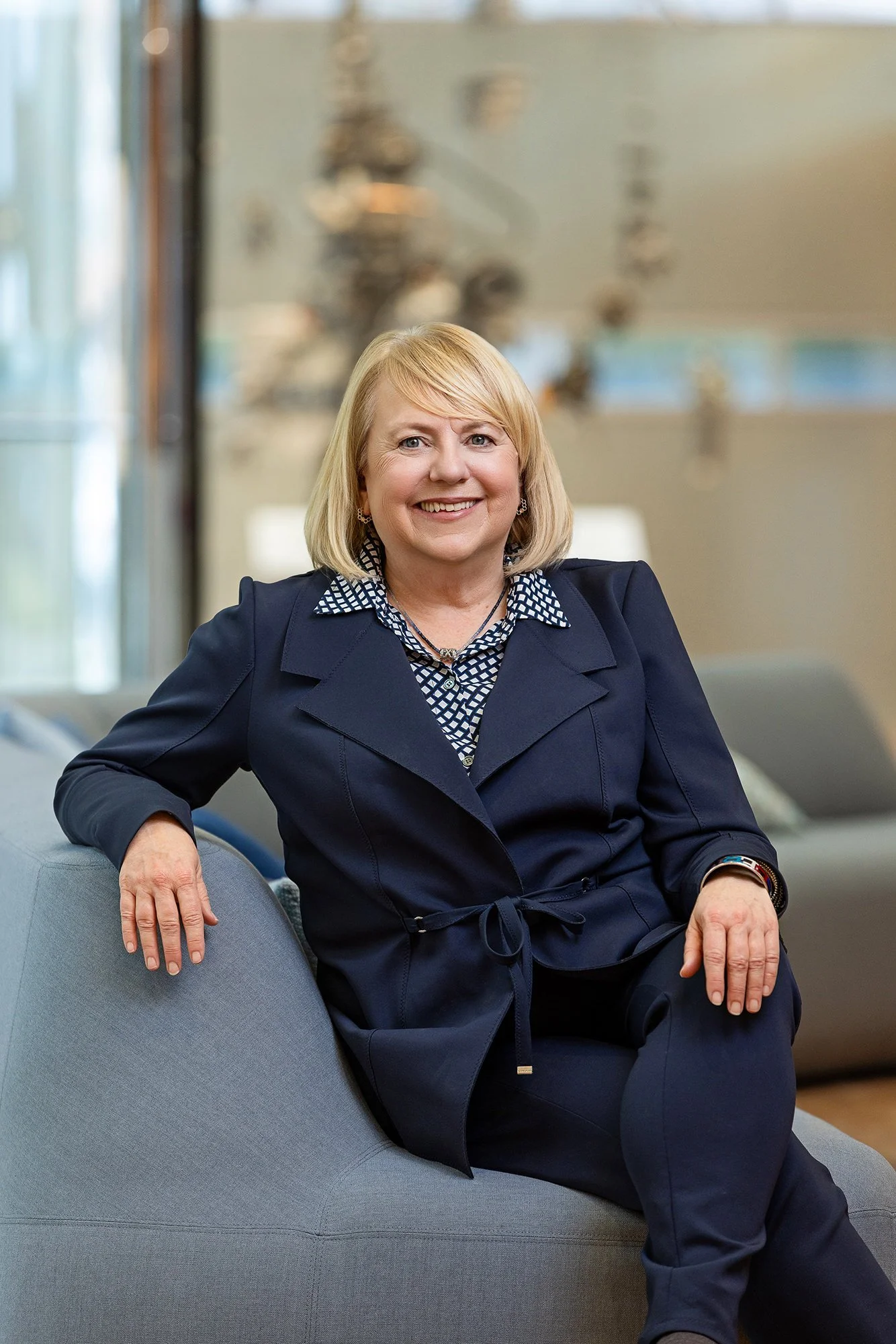 Executive in a navy suit seated on a lounge chair in a bright lobby, Cummins corporate portrait