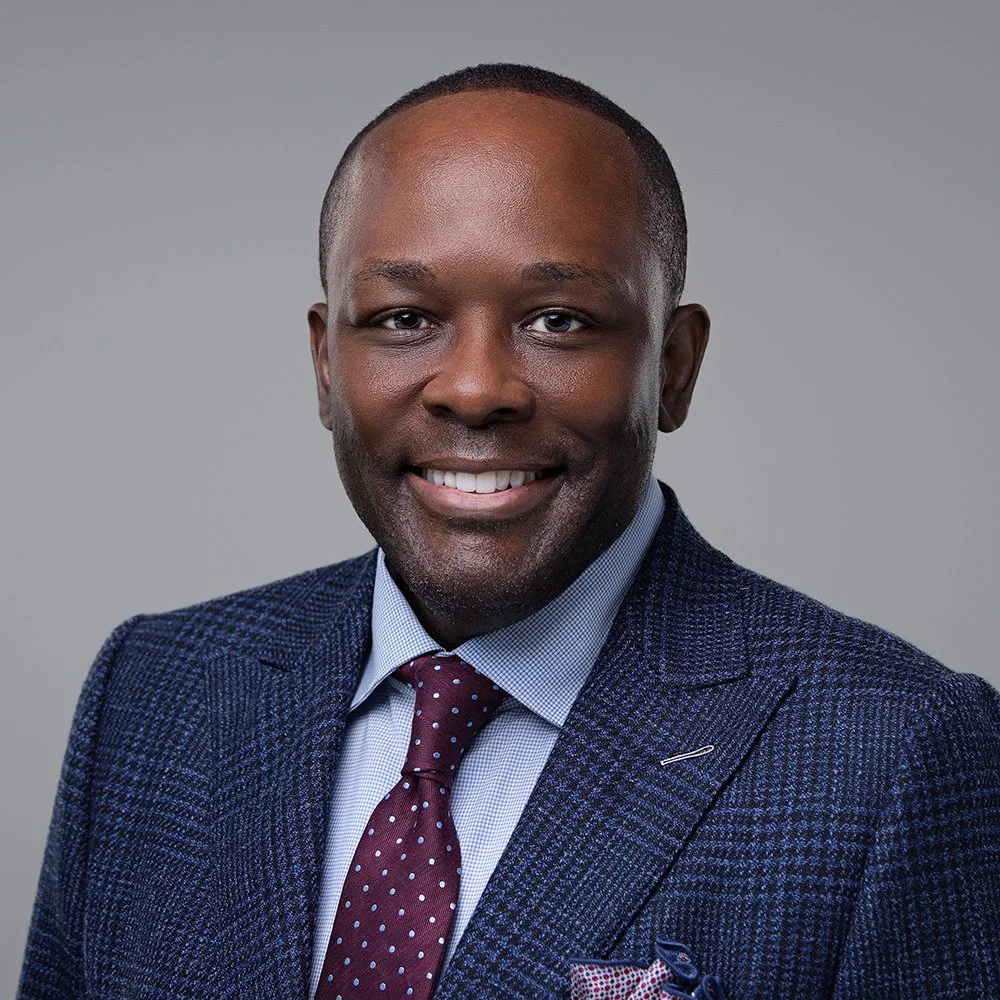 Smiling businessman in a navy suit and burgundy tie, executive headshot by Square Mouth Studios