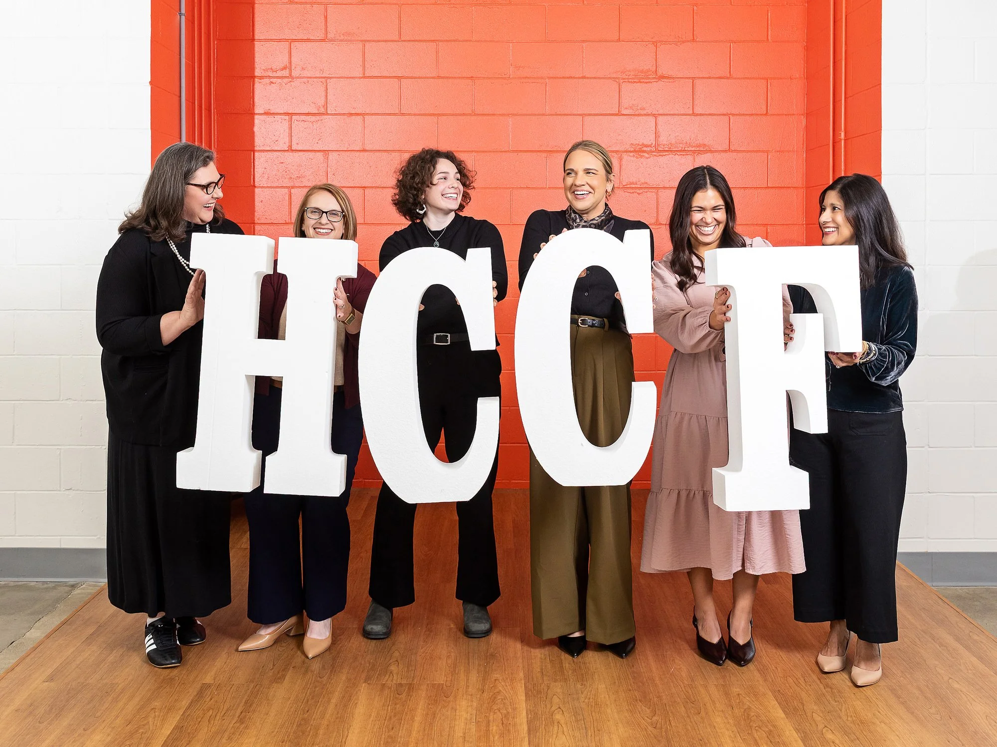 Hamilton County Community Foundation team posing with large HCCF letters in front of an orange wall