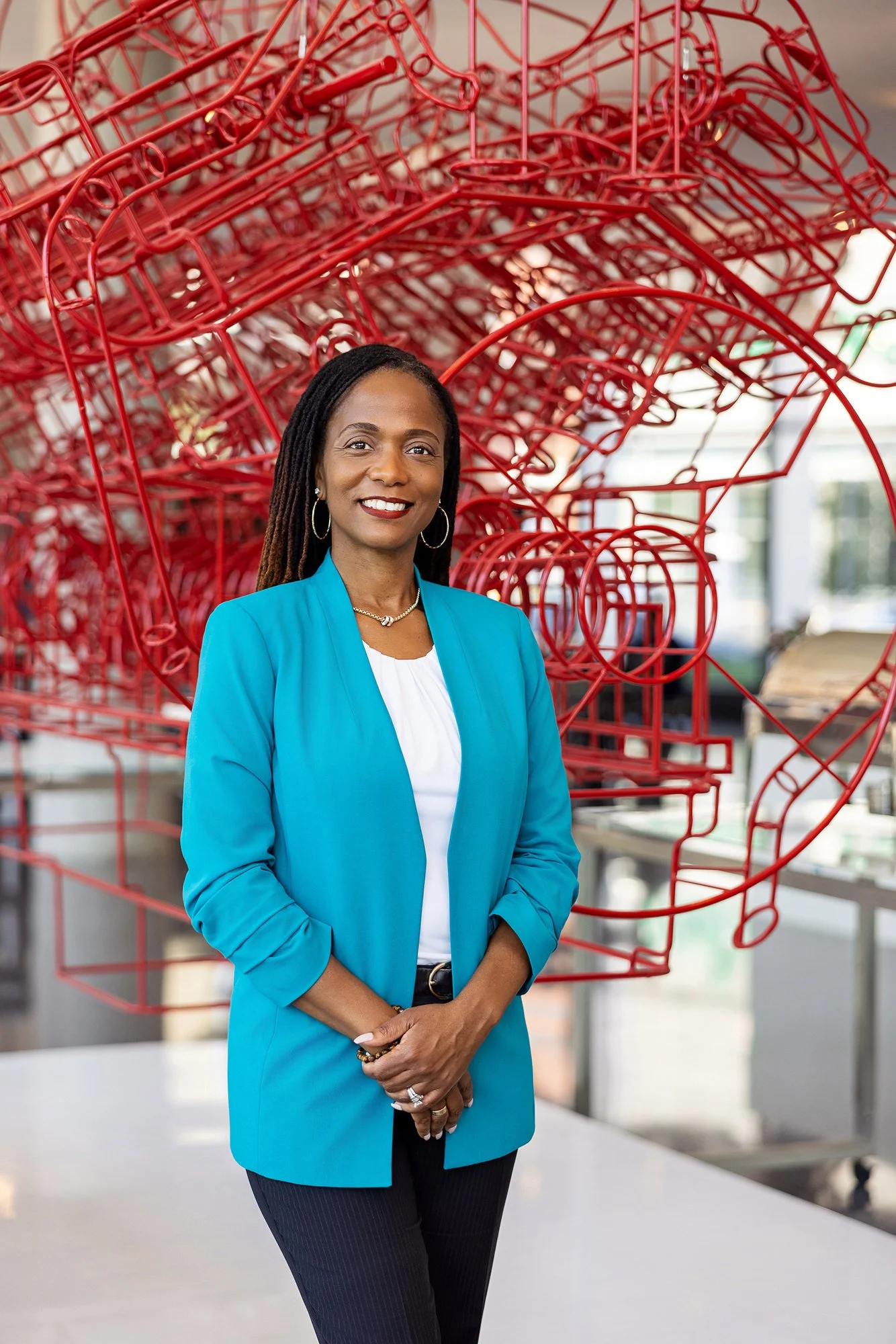 Woman in a teal blazer beneath a red sculptural installation, Cummins corporate portrait in Indianapolis
