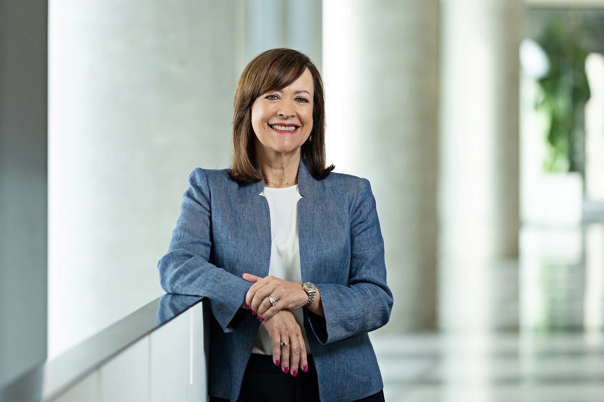 Smiling woman in a light blue blazer leaning on a railing, corporate portrait for Cummins