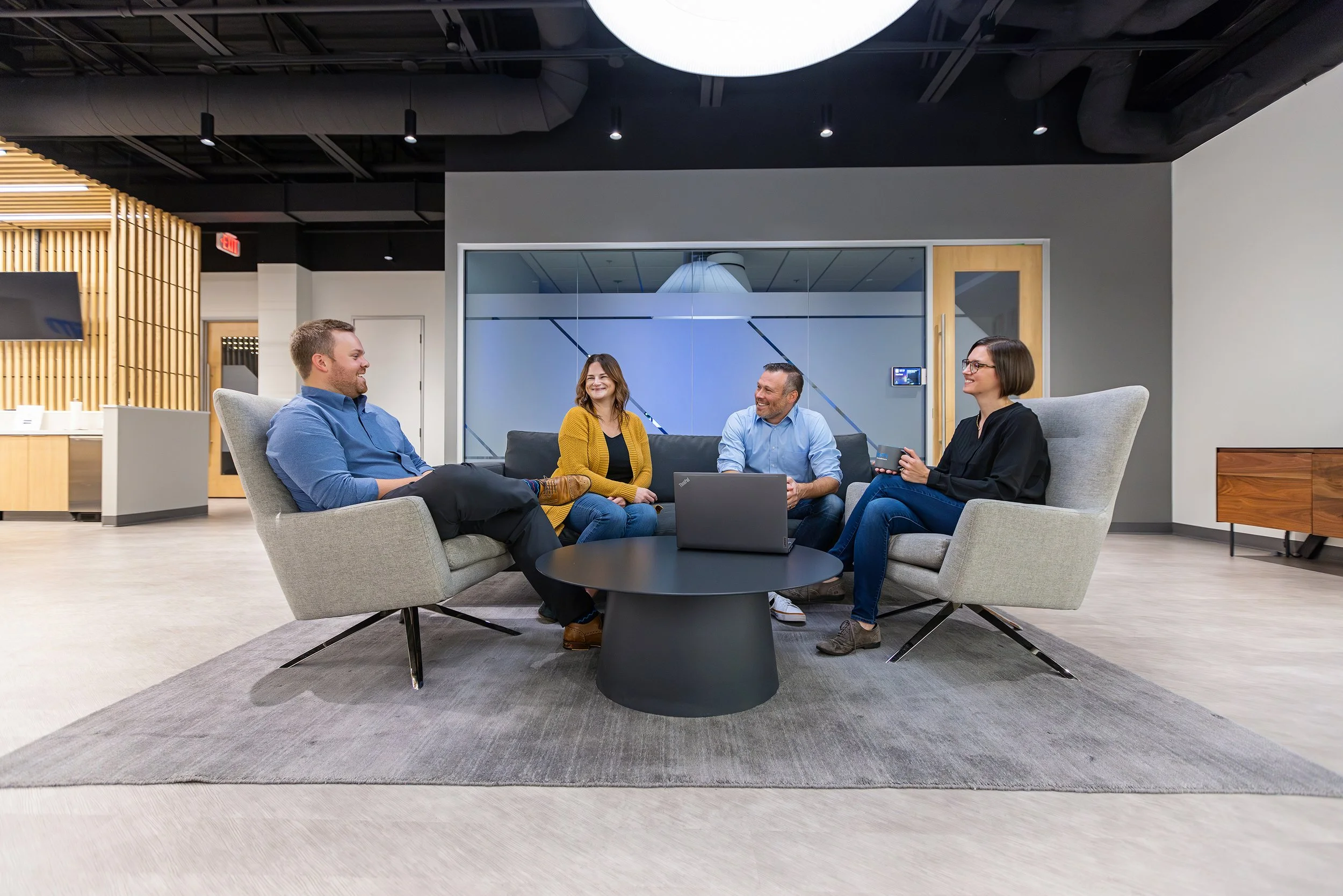 Coworkers meeting in a modern glass-walled office lounge, brand photography for KSM in Indianapolis