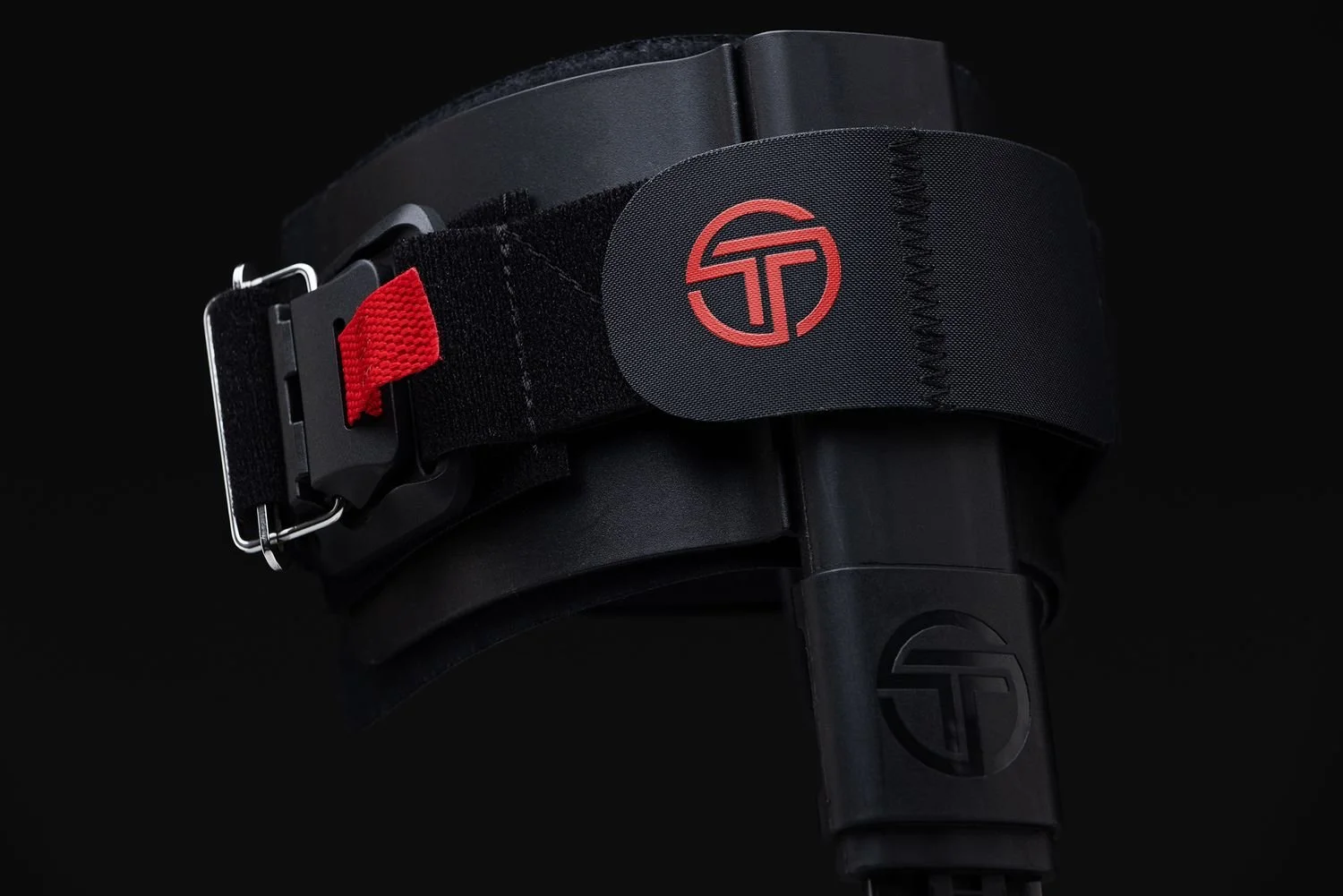 Black orthopedic strap with a red buckle on a dark background, product photo for Thrive Orthopedics in Fishers
