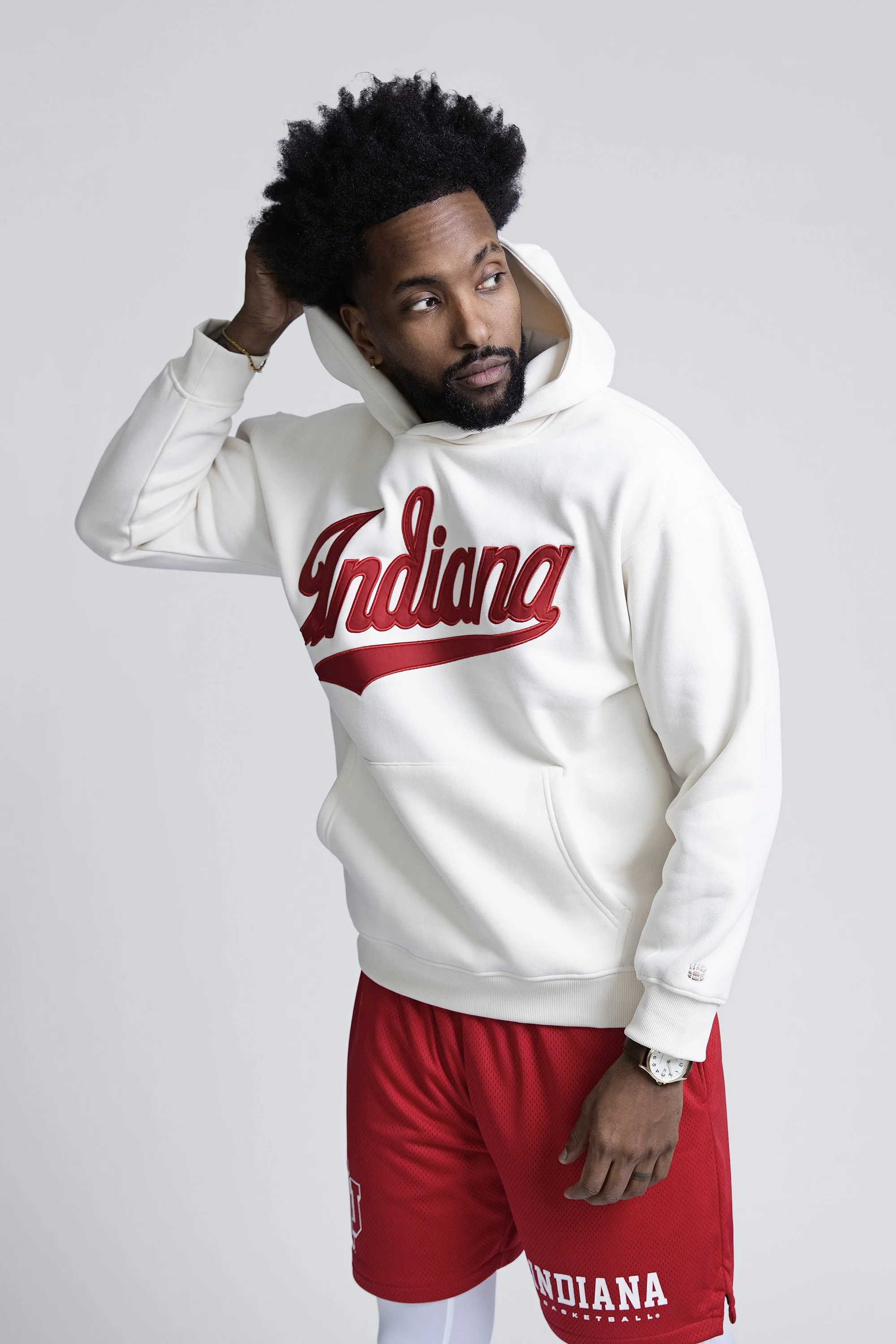 Model in a cream Indiana hoodie and red shorts, Homefield Apparel studio photography in Fishers
