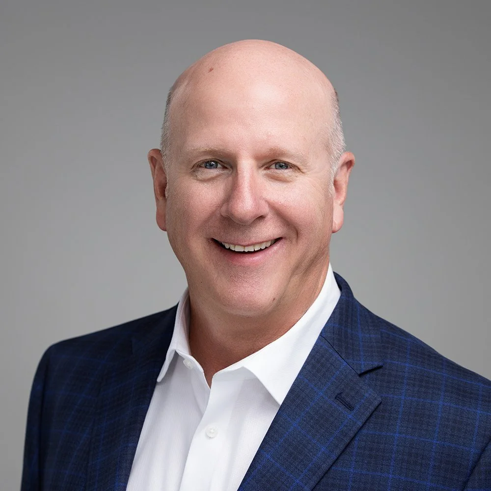 James Bradley smiling in a navy blazer and white shirt, business headshot