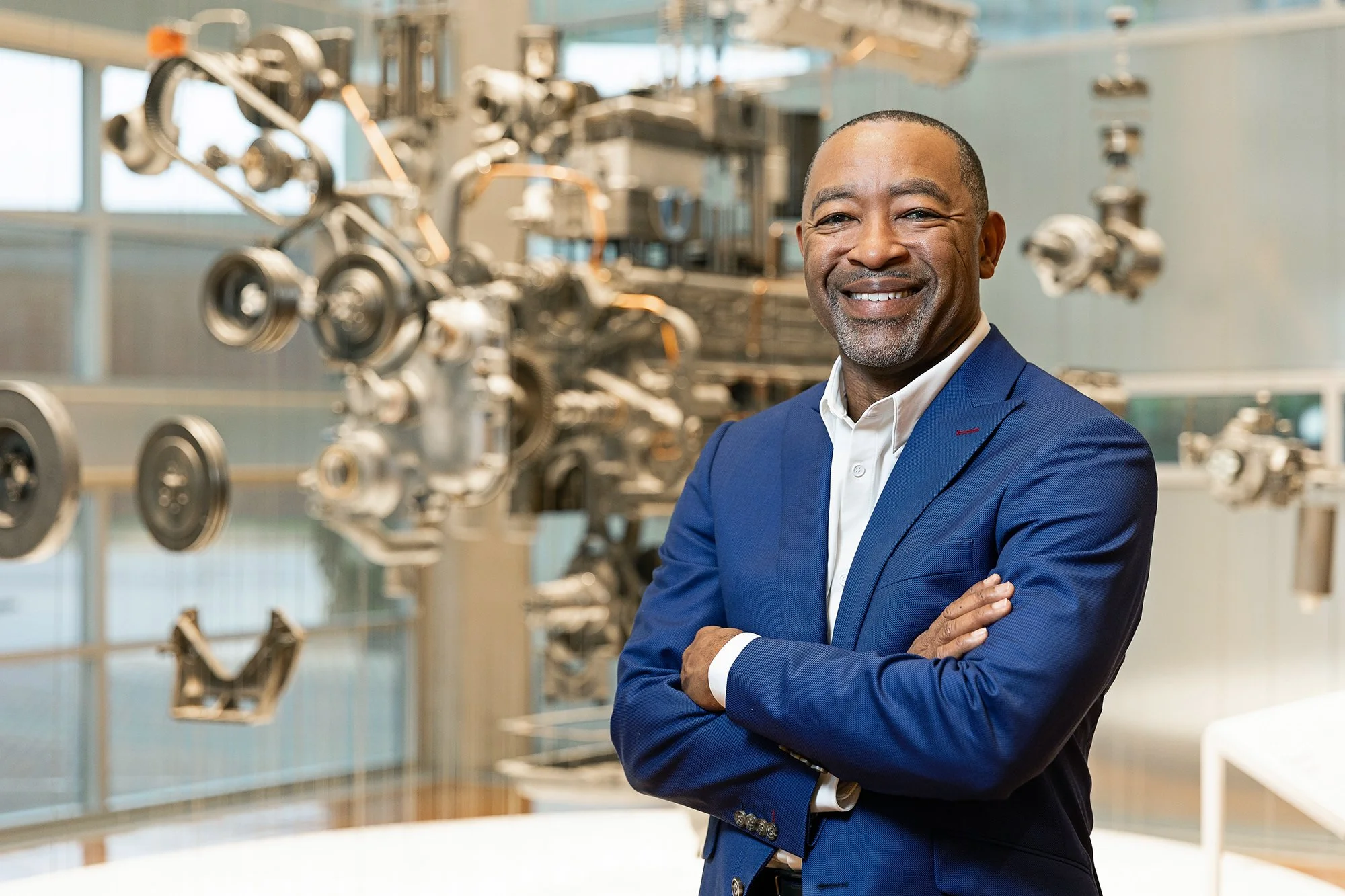 Smiling executive in a blue suit beside a metallic sculpture, Cummins corporate portrait