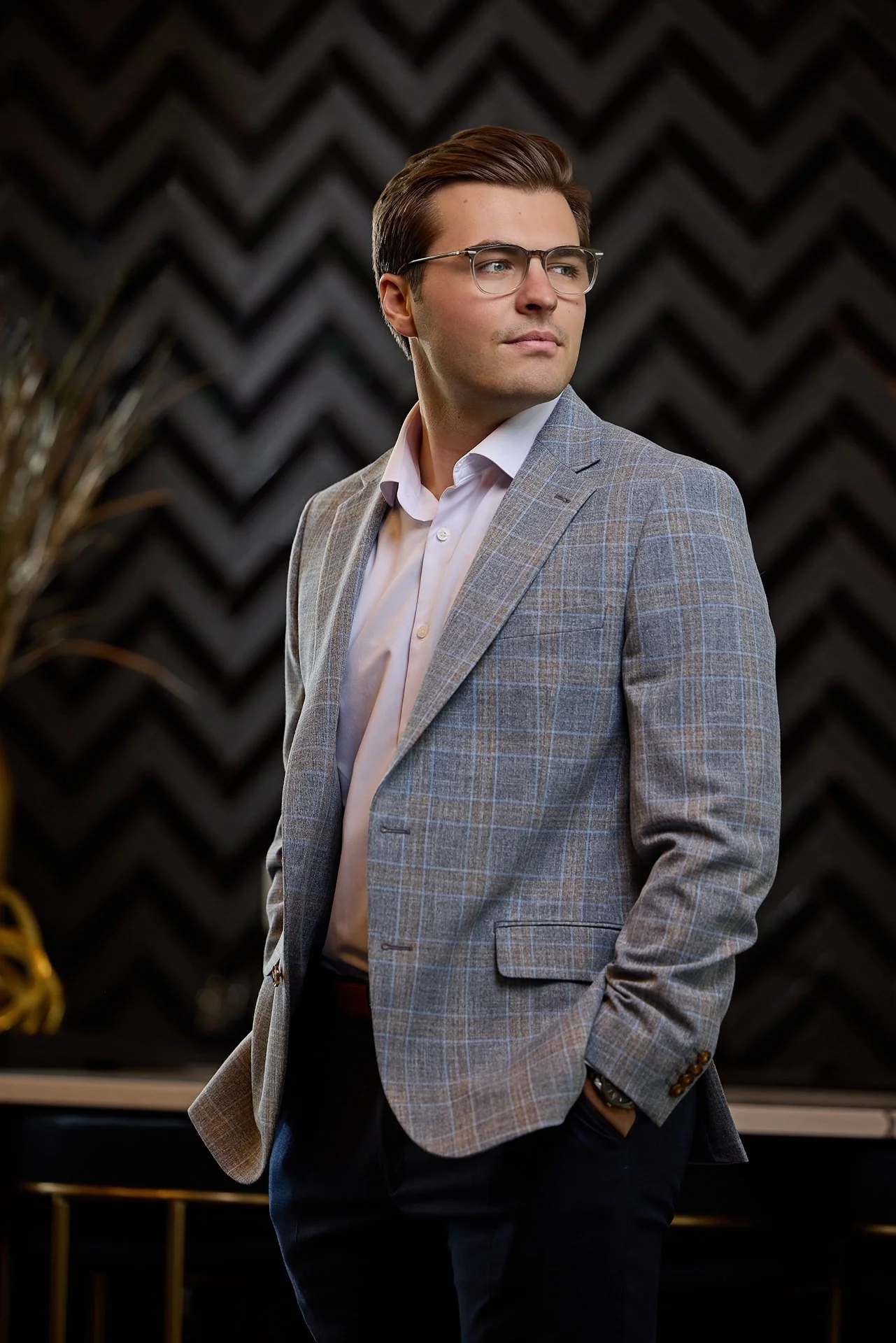 Professional in glasses and a plaid sport coat posing against a black chevron wall, branding portrait in Fishers, Indiana