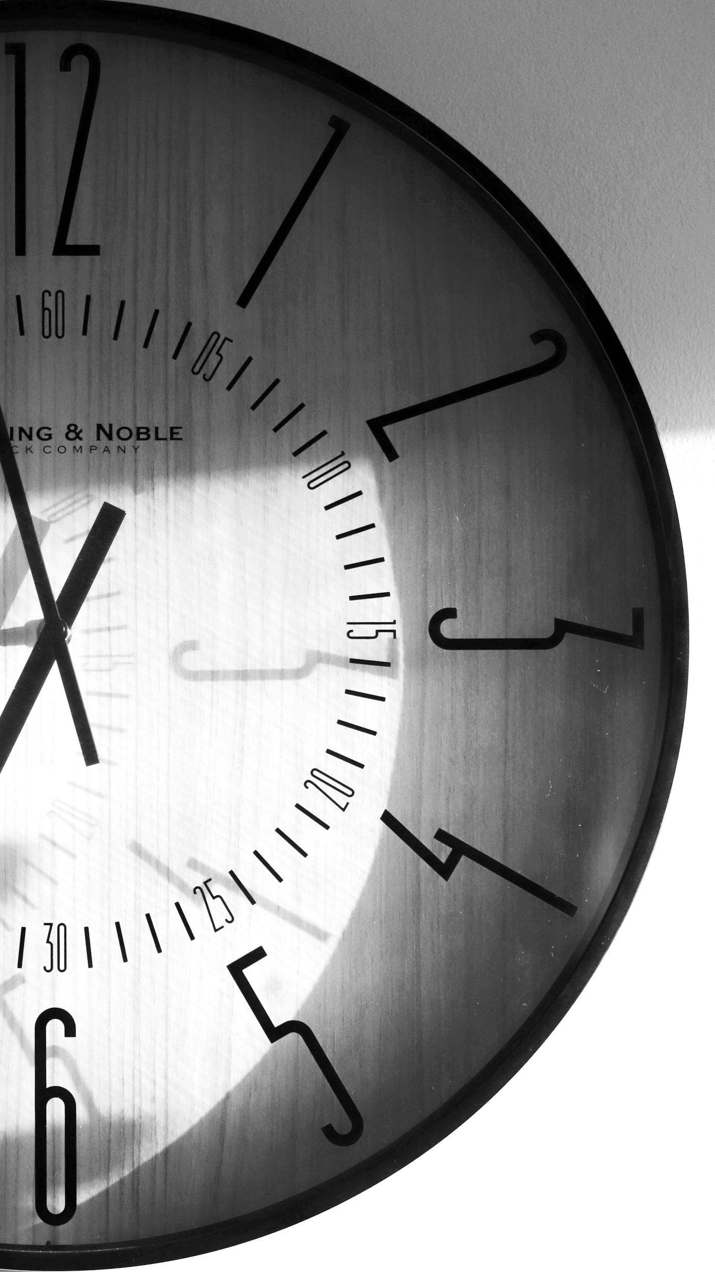 Close-up of a large modern wall clock showing the time approximately 10:52 in black and white.