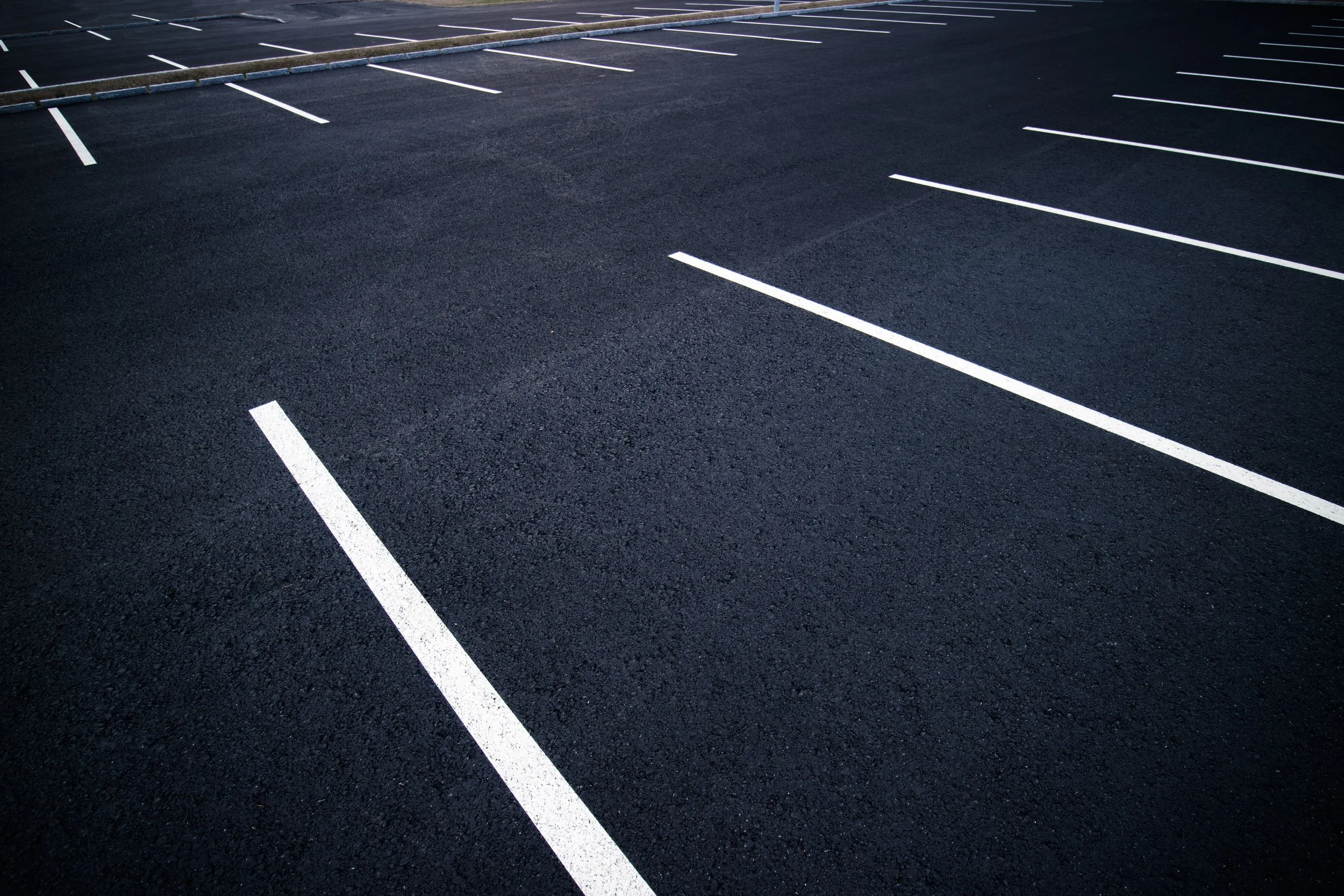 Empty parking lot with white lines on dark asphalt.