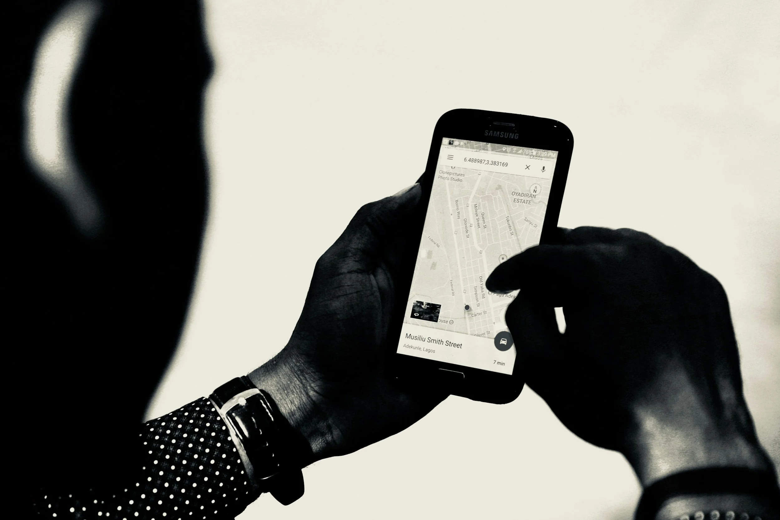A person holding a smartphone with a map app open, showing street names and navigation directions.