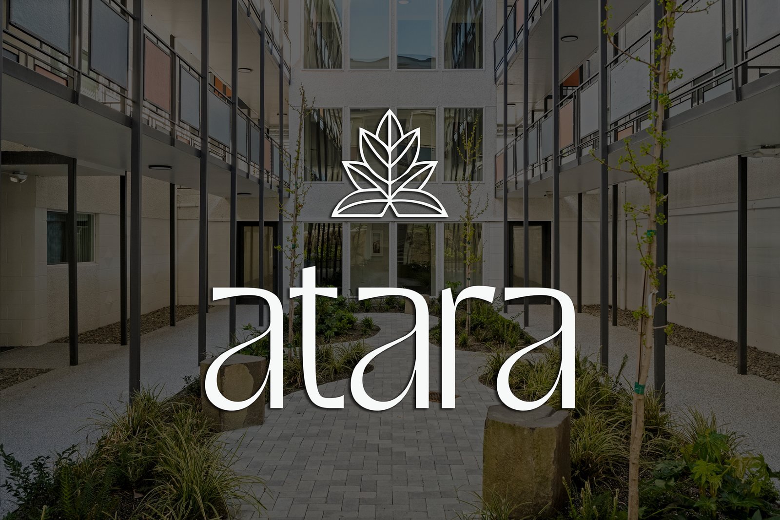A modern apartment building courtyard with landscaping and the word 'atara' overlayed, along with a logo of a stylized leaf.