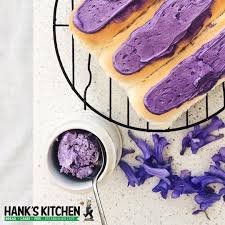 Purple frosting on cookies with extra frosting spread on a surface, with a small bowl of purple frosting next to them.