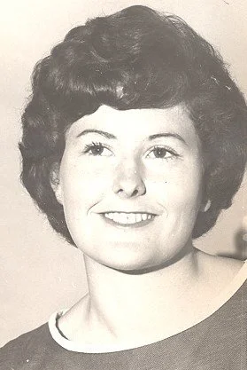 Black and white photograph of a woman with short, curly hair smiling at the camera.