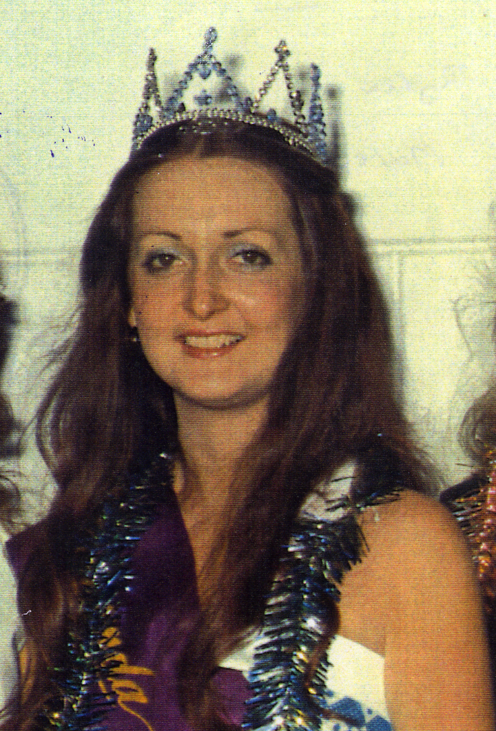 Woman wearing a crown and a sash, celebrating at a pageant or contest.