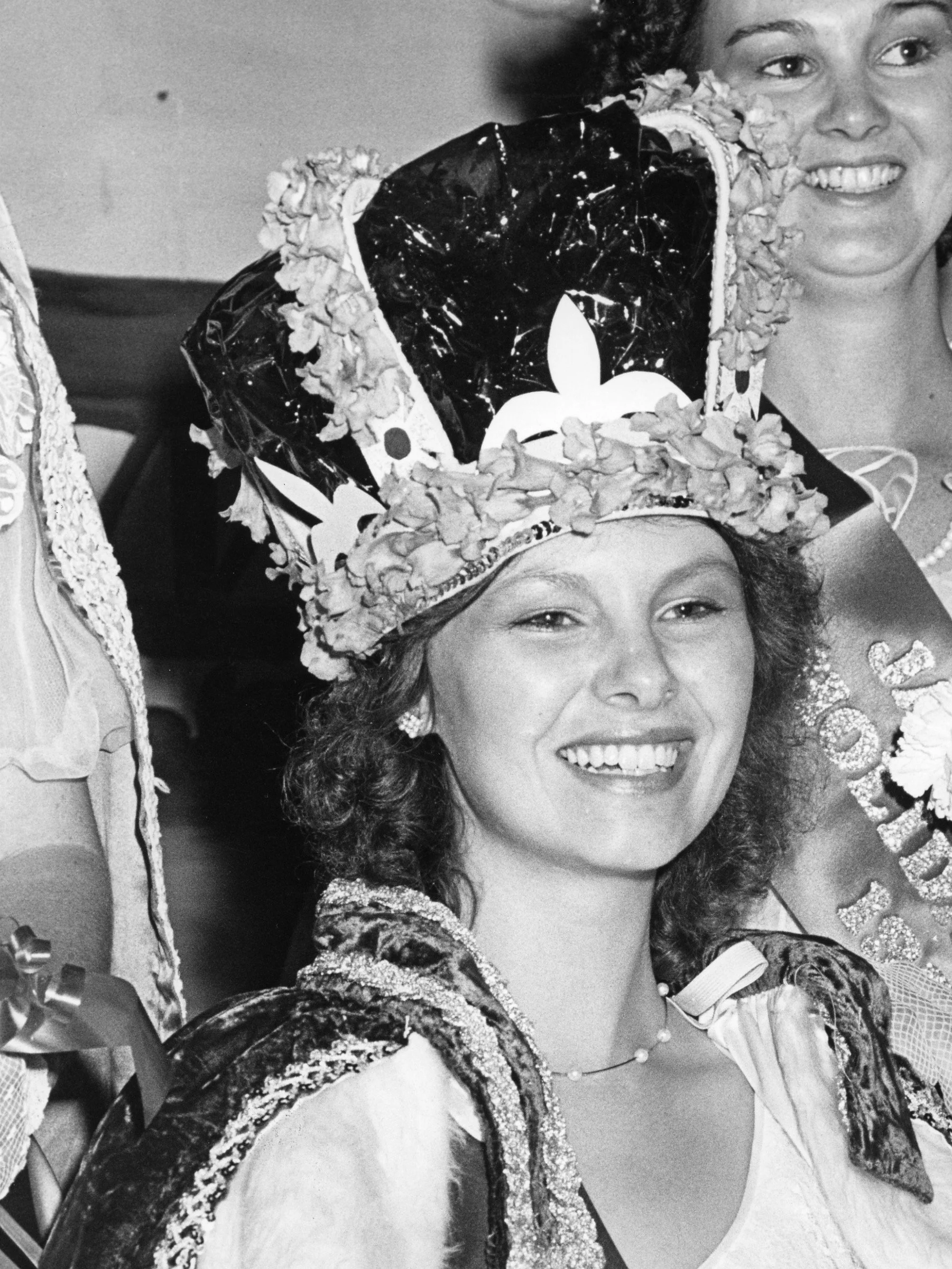 Black and white photo of two women in princess crowns, smiling and dressed in decorated clothing, celebrating a special occasion.