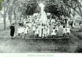 A group of children posing outdoors with a carnival or festive display behind them, possibly a photo from a fair or celebration.