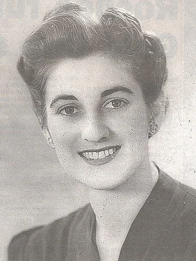 Black and white portrait of a young woman with short wavy hair, smiling and wearing a dark top.
