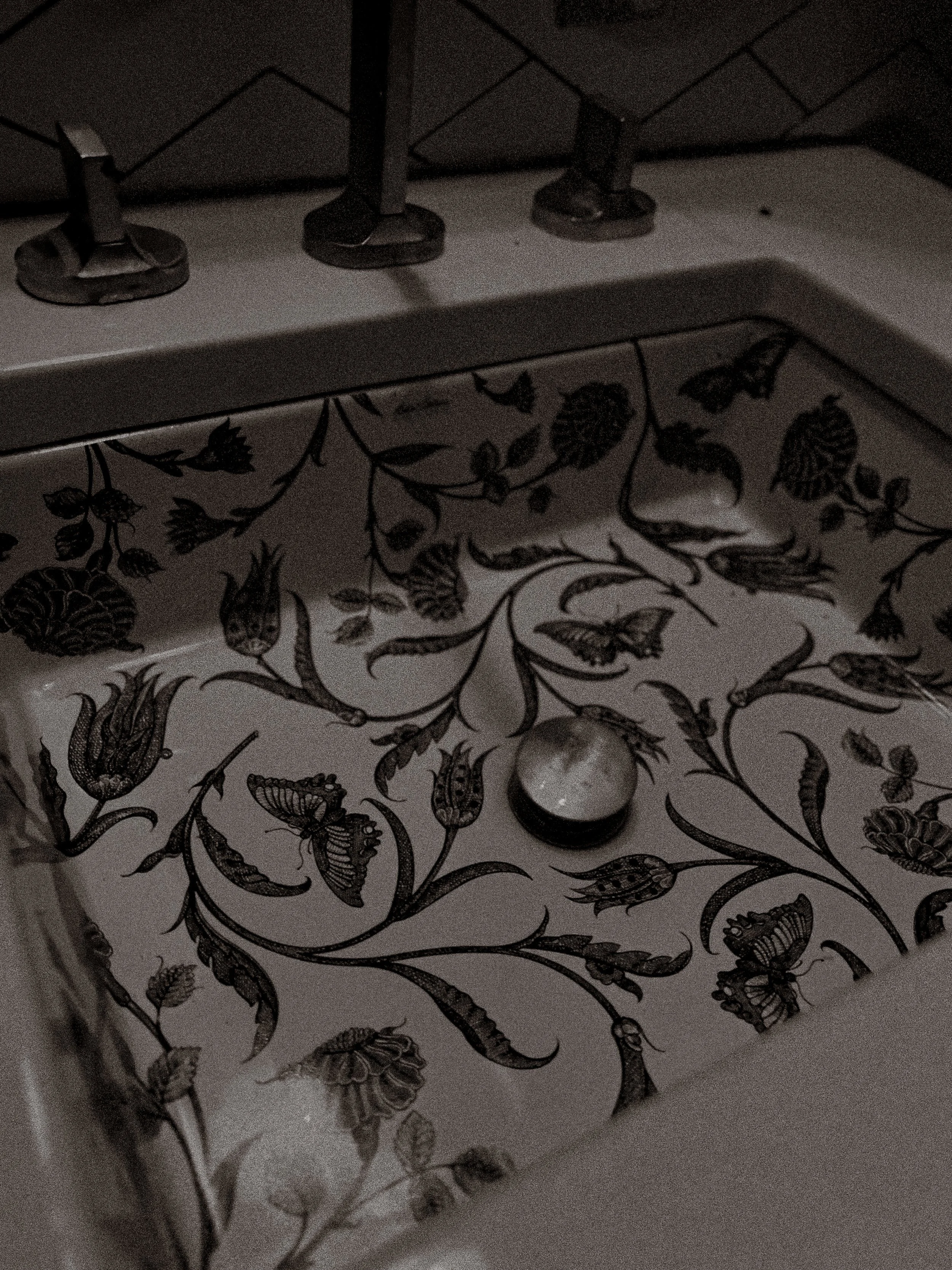 Close-up of a patterned surface with black and white botanical illustrations, and three metal keys attached to a metal rail.