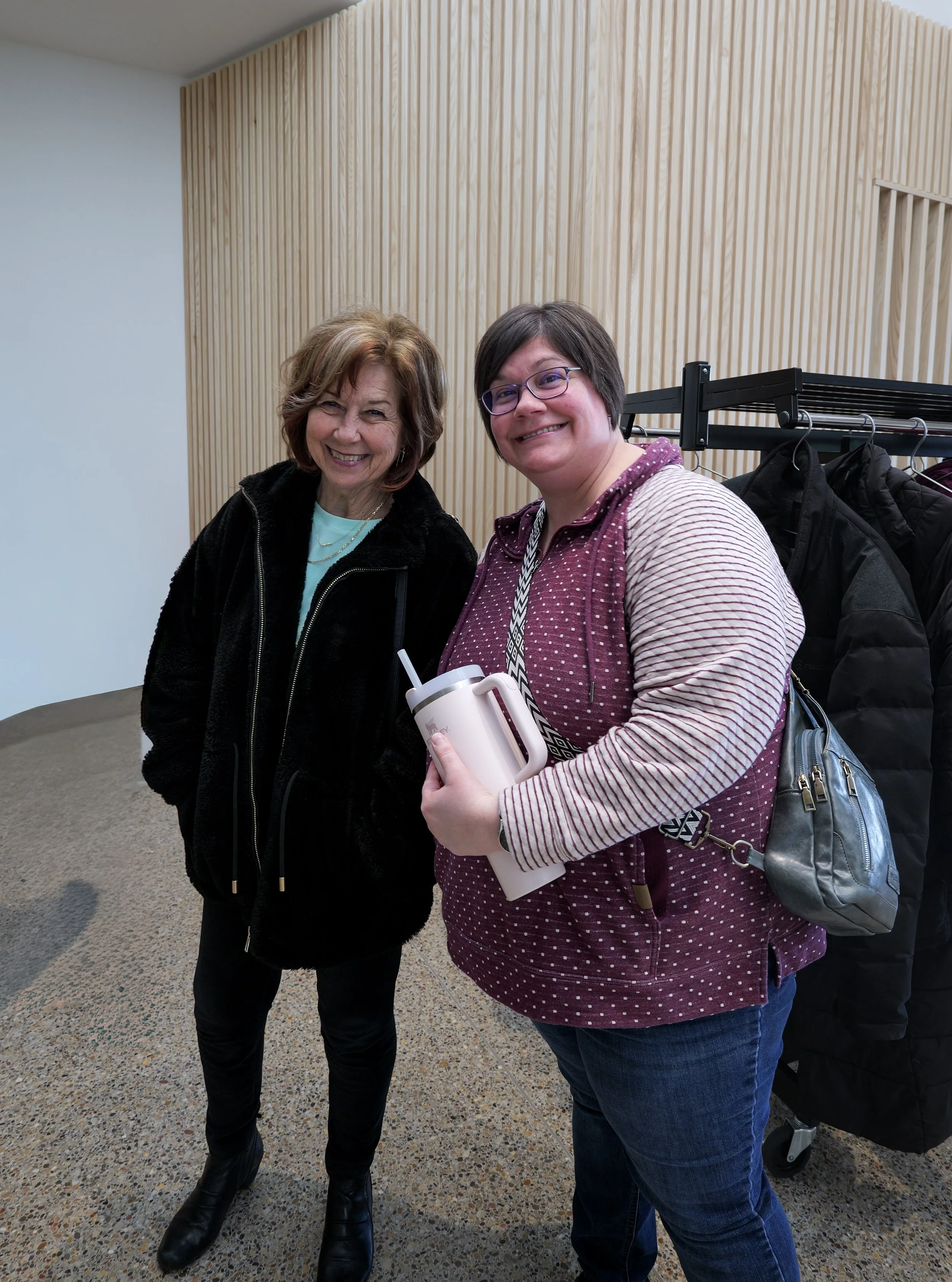Diverse group of churchgoers attending a church near me in a room with wooden panel walls and black curtains, some people raising their hands.