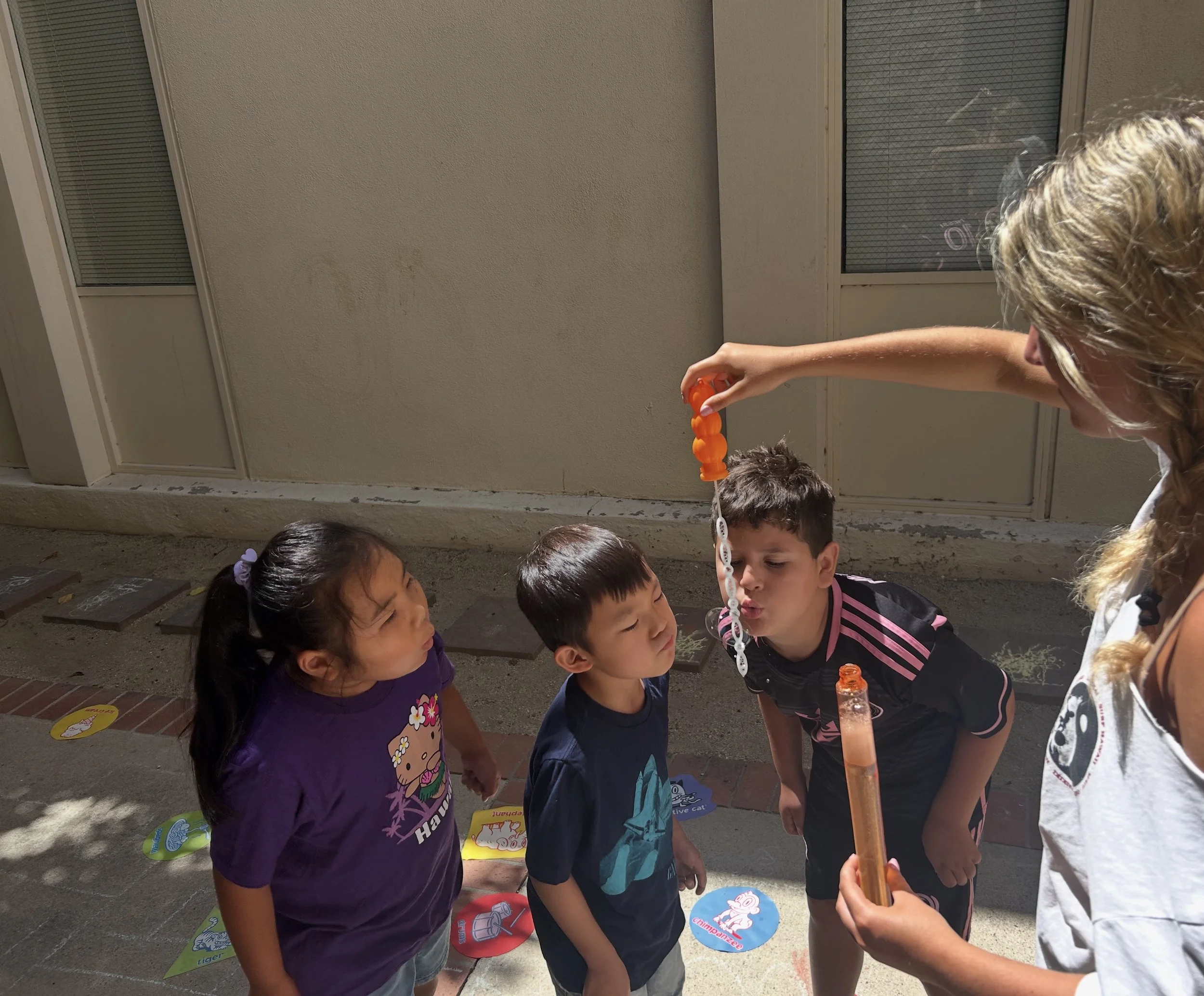 Children blowing bubbles outside at Friendship Builders social skills group