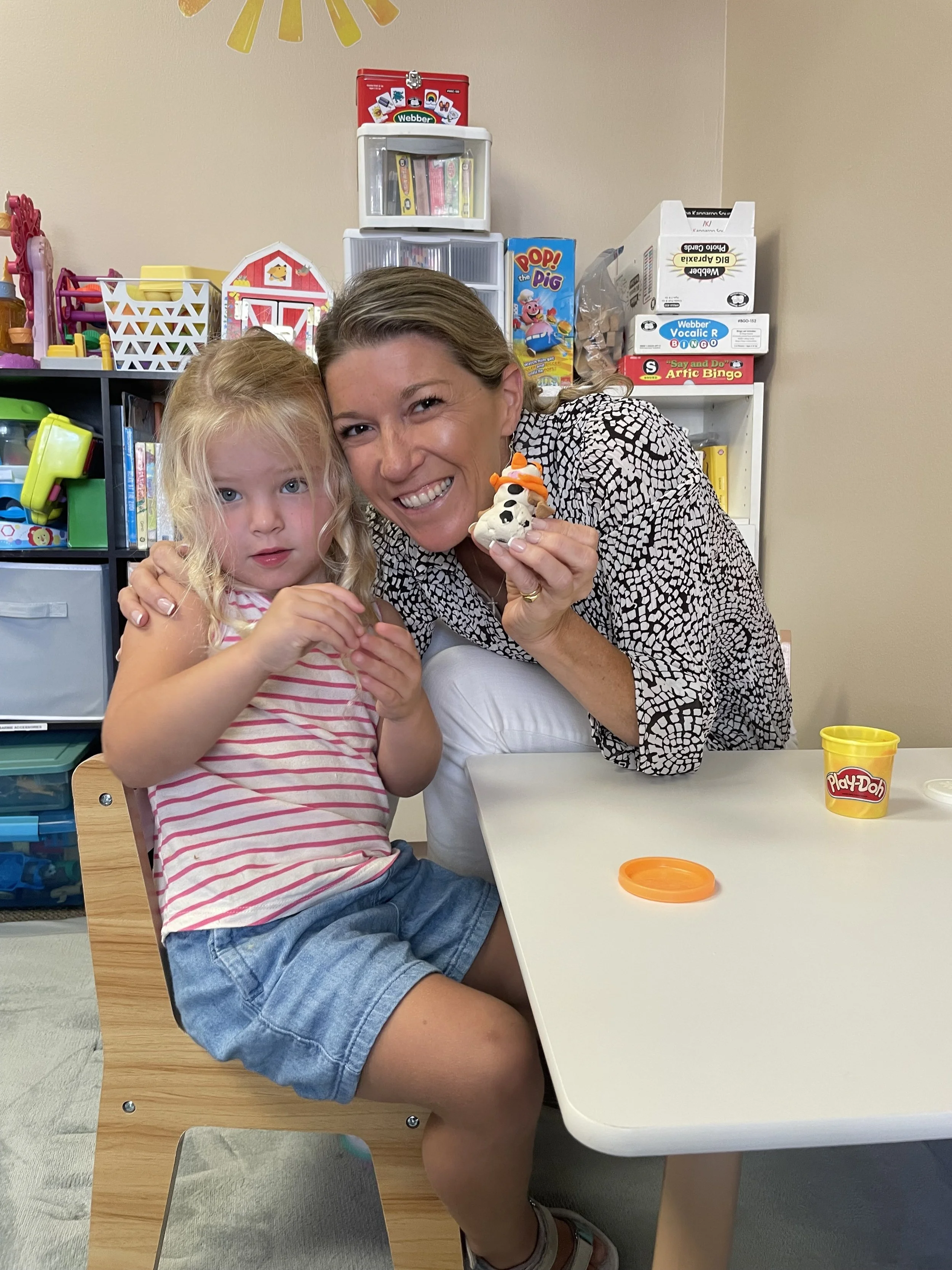 Pediatric speech therapist and owner of Friendship Builders in Newport Beach engaging in play-based speech therapy with a child using playdough to improve social skills and emotional regulation.