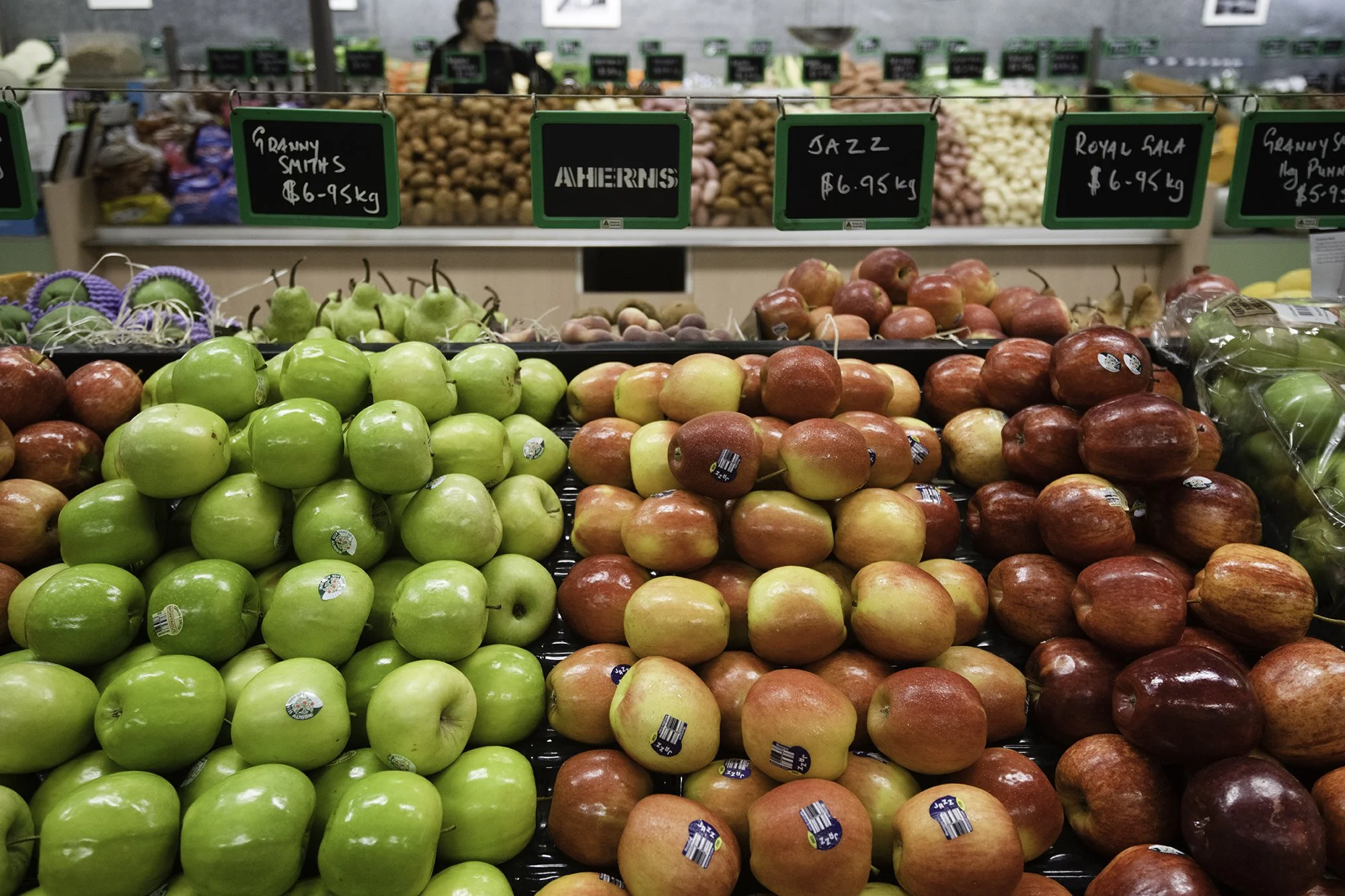 Display of green, red, and yellow apples at a grocery store produce section.