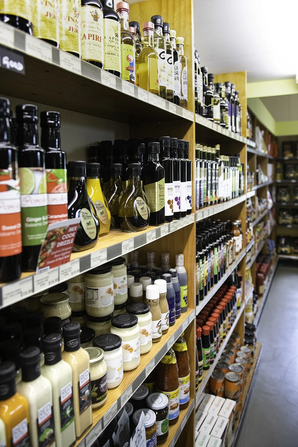 Store aisle with shelves stocked with bottles of cooking oils, sauces, and condiments.