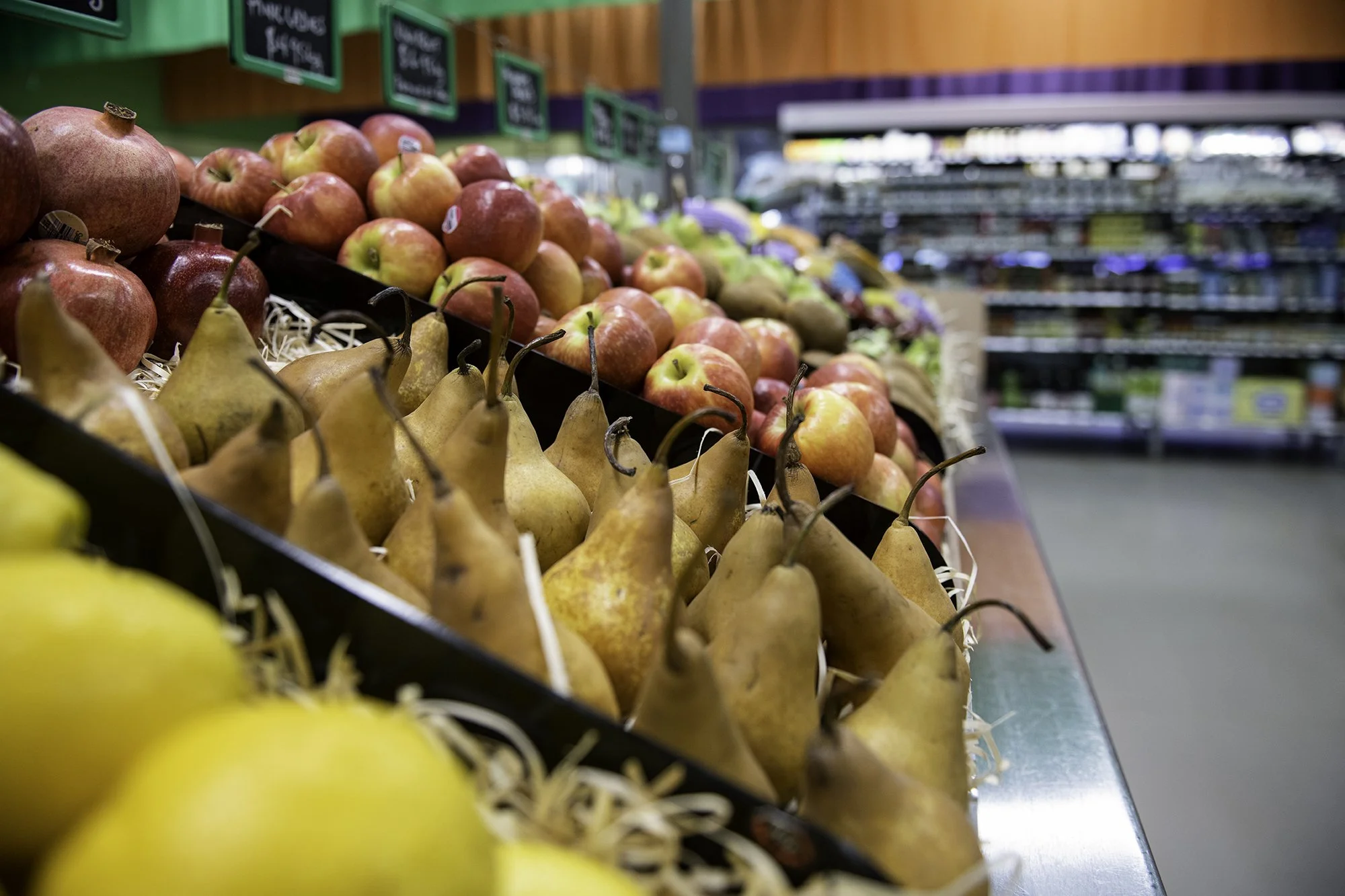 A display of fresh apples, pears, and bananas in a grocery store produce section.