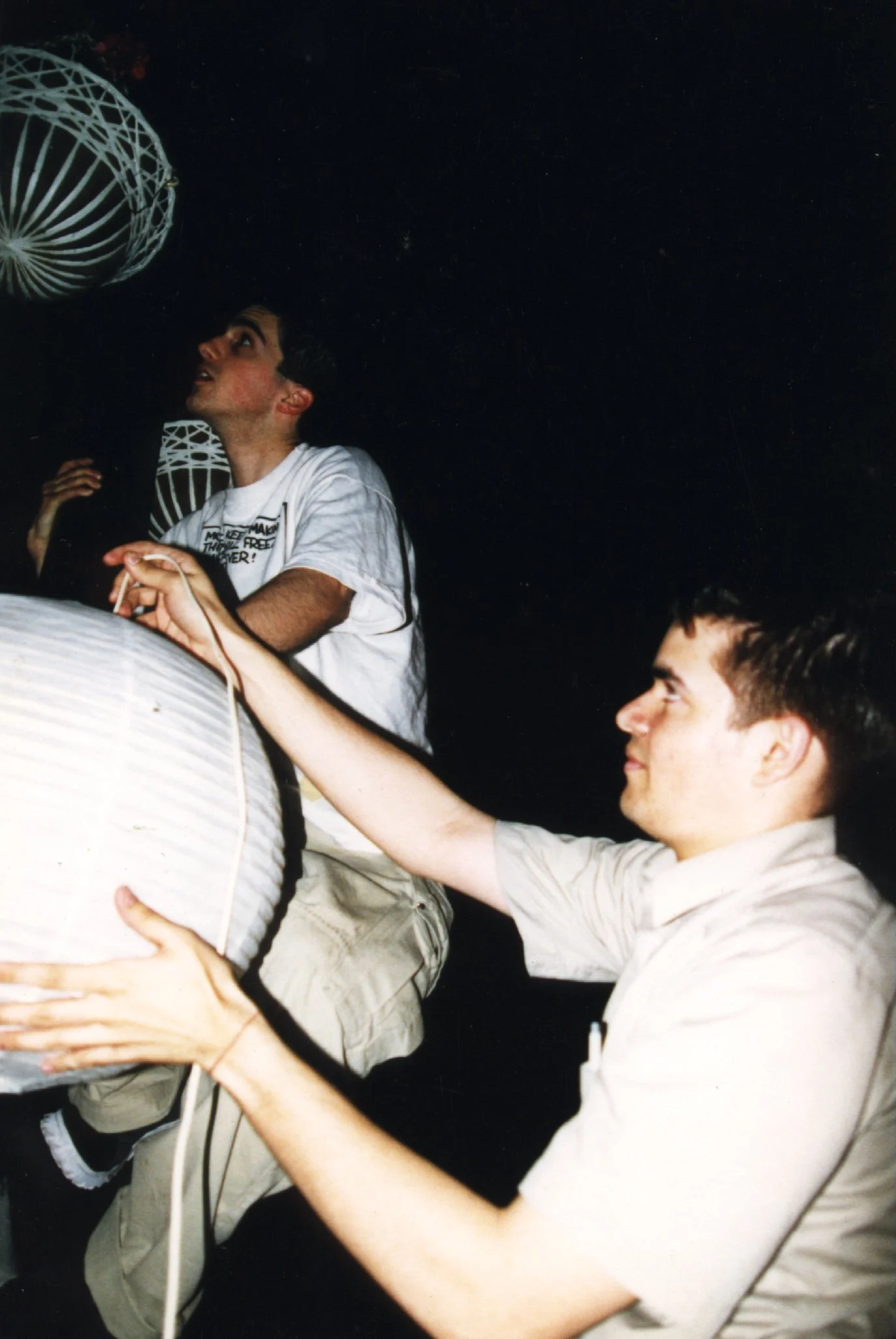 Independent filmmakers hanging a japanese lantern on a streetlamp for cinematic lighting while producing 90s NYC indie movie 'Threat'.