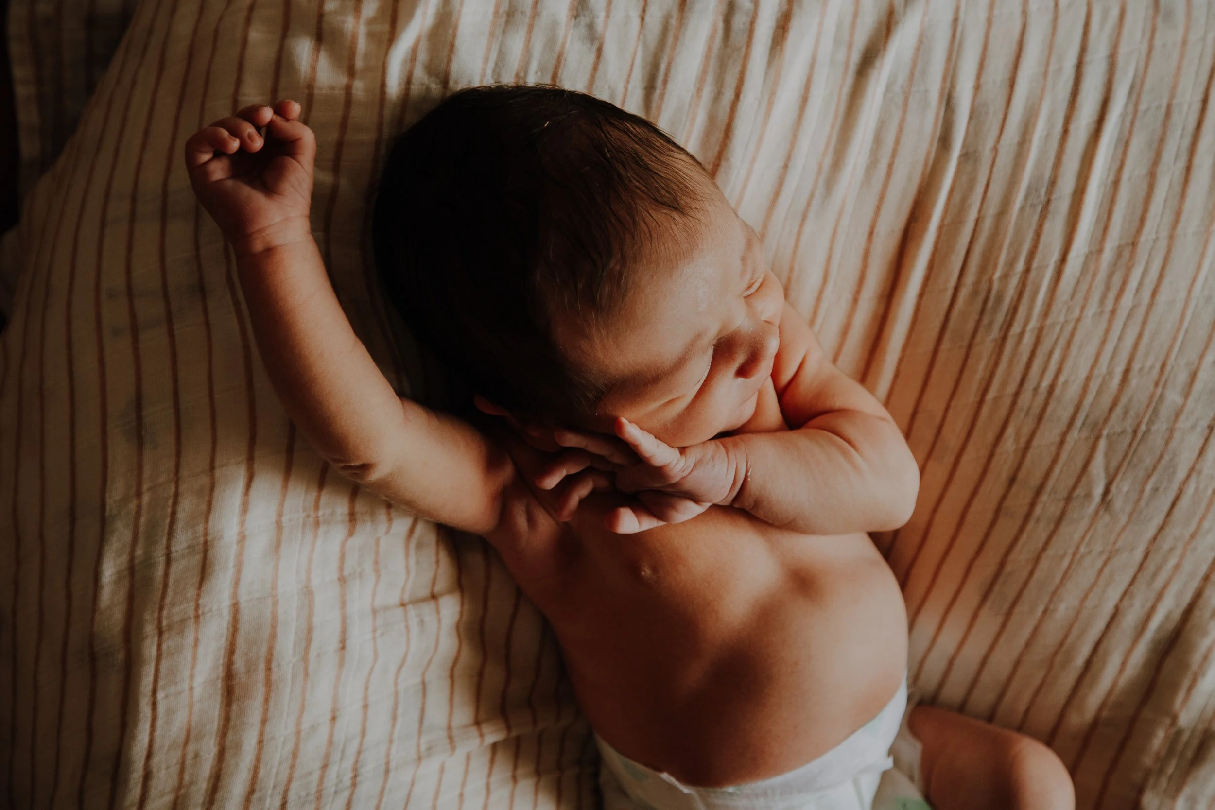Newborn baby, stretching their arms.