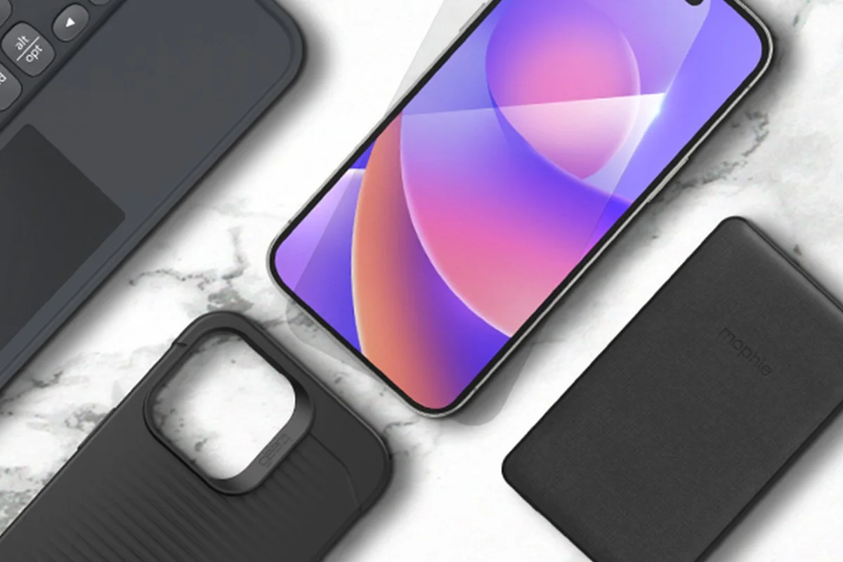 An iPhone with a colorful screen, a black Mophie power bank, a black Mophie phone case, and a black Bluetooth keyboard on a white marble surface.