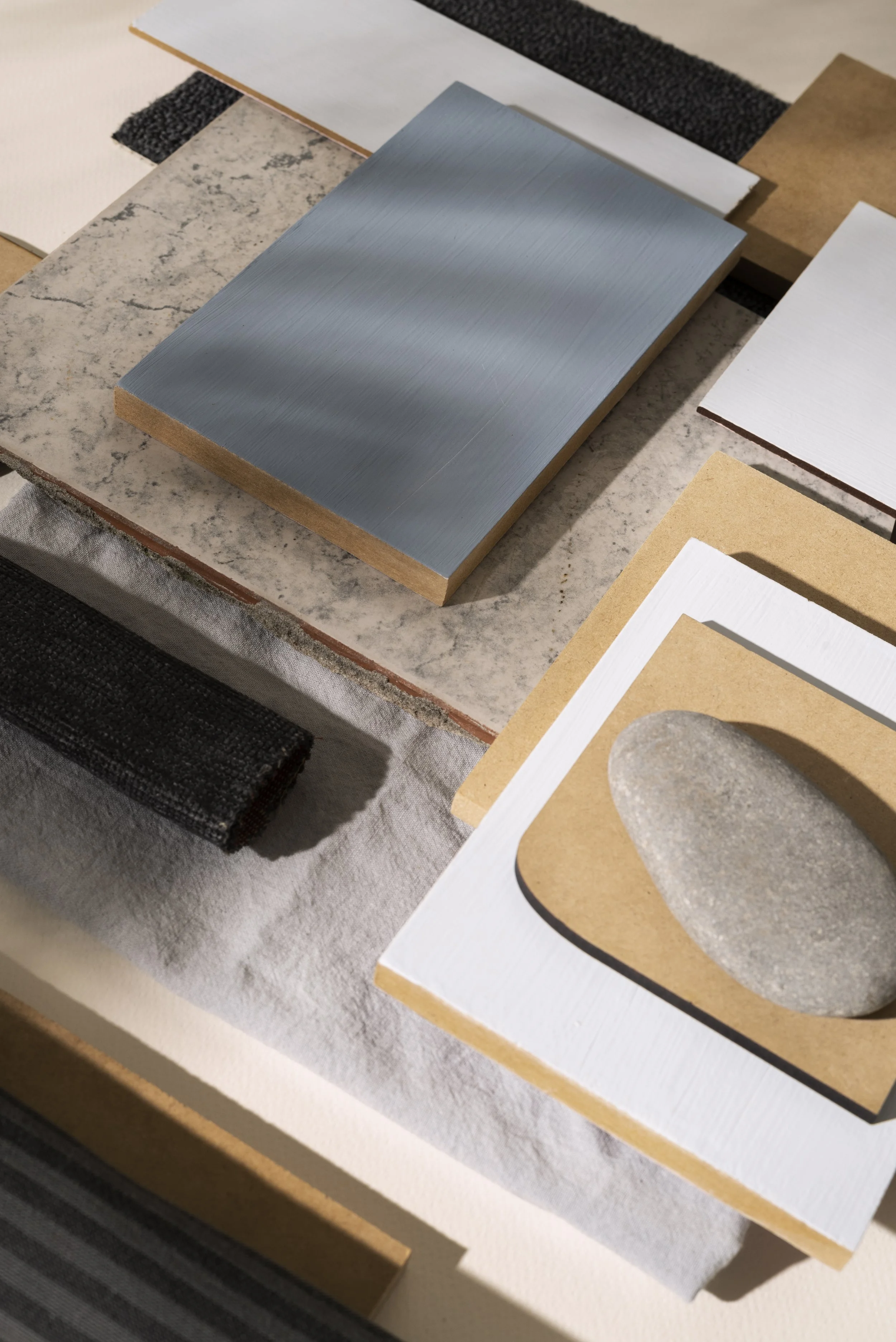 Array of different tiles and stones, including marble, ceramic, and textured materials, arranged on a surface.