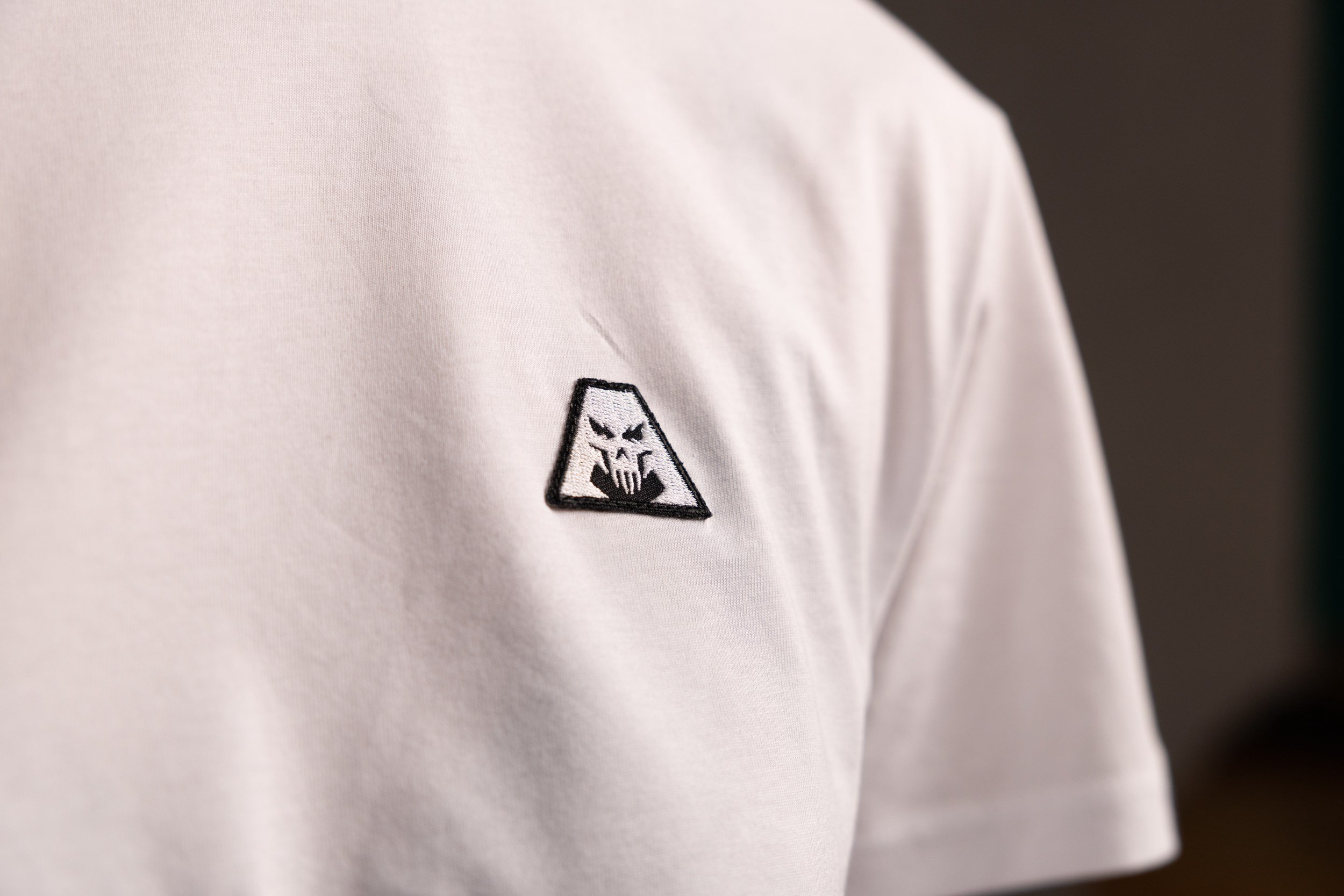 Close-up of the woven Astratius A icon patch on a white t-shirt