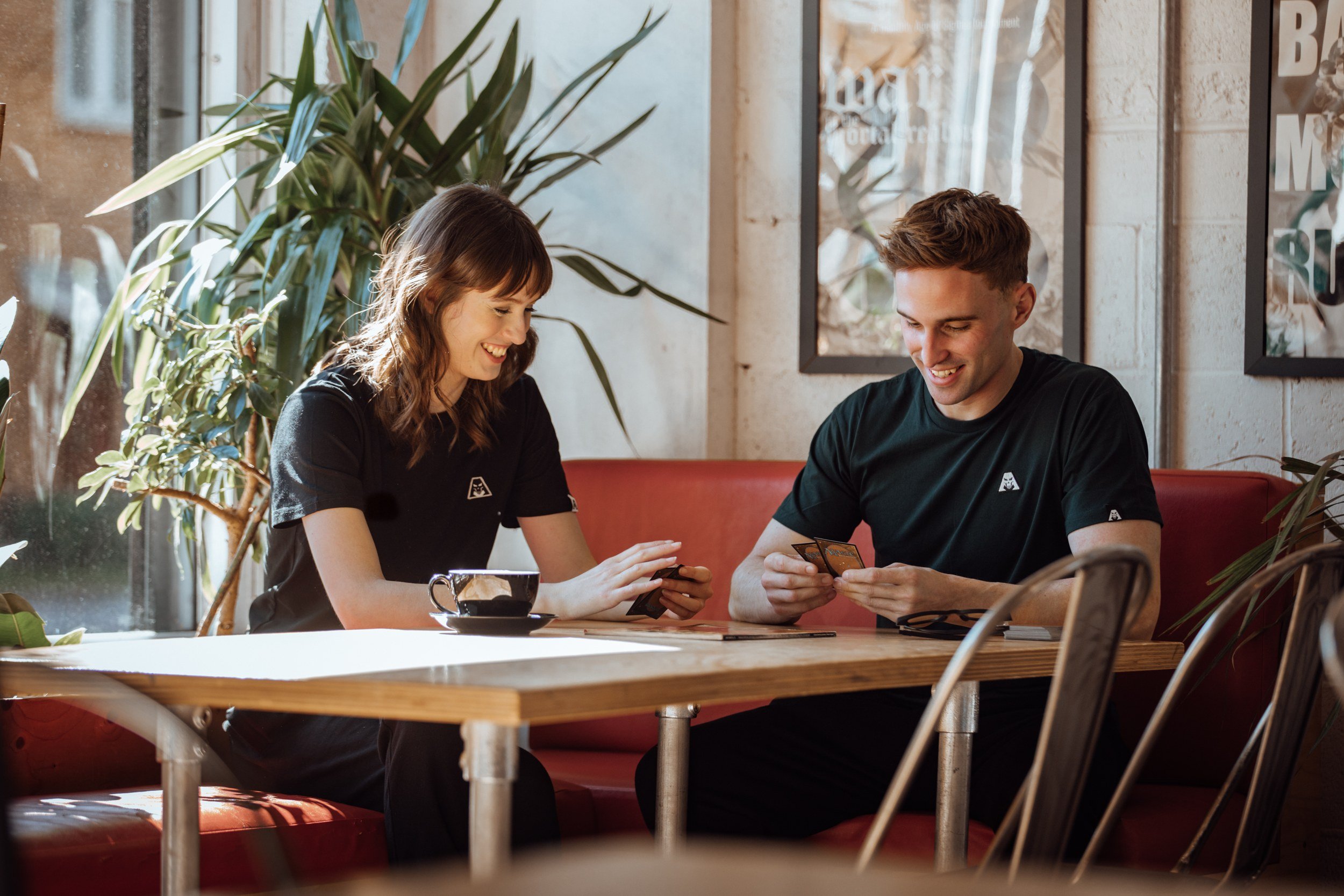 Two friends at a café table wearing Astratius tees