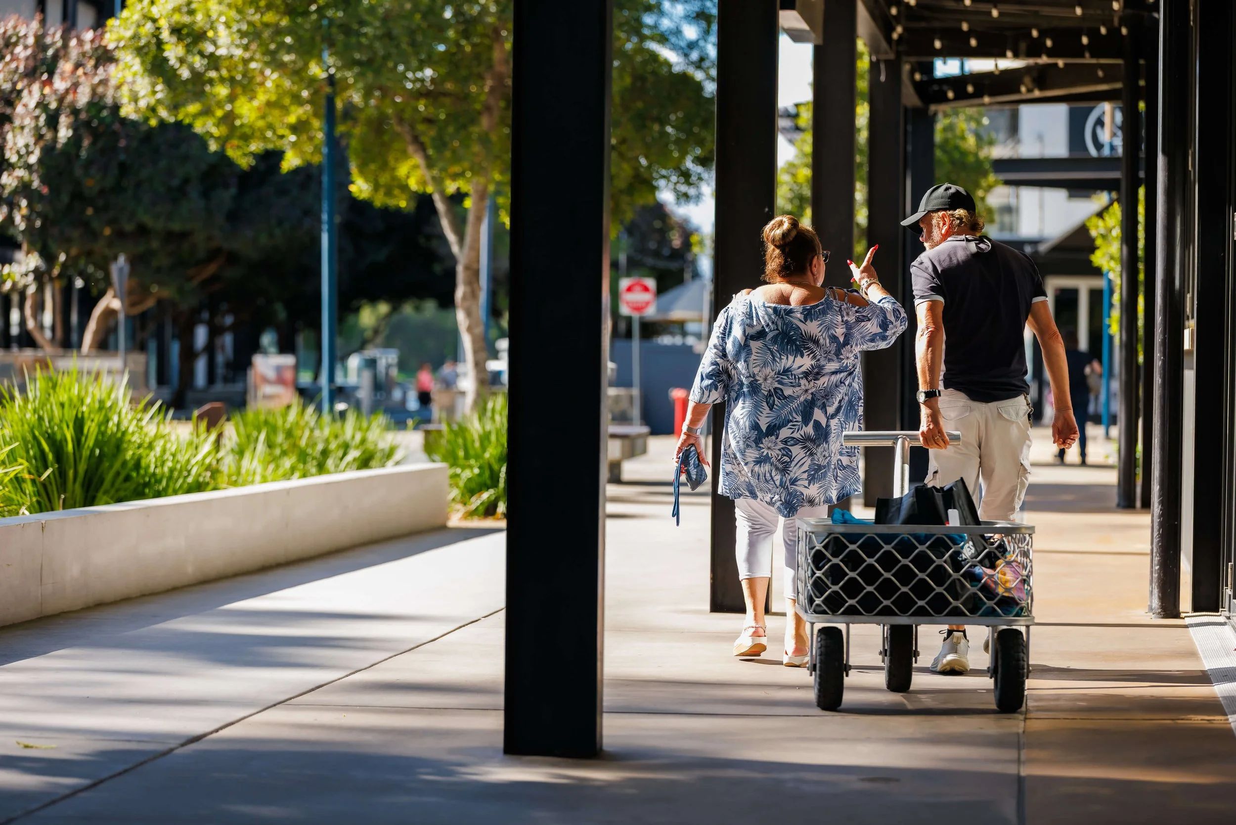 A woman and a man pushing a cart with marine supplies outside of a store, with the woman talking and gesturing towards the man.