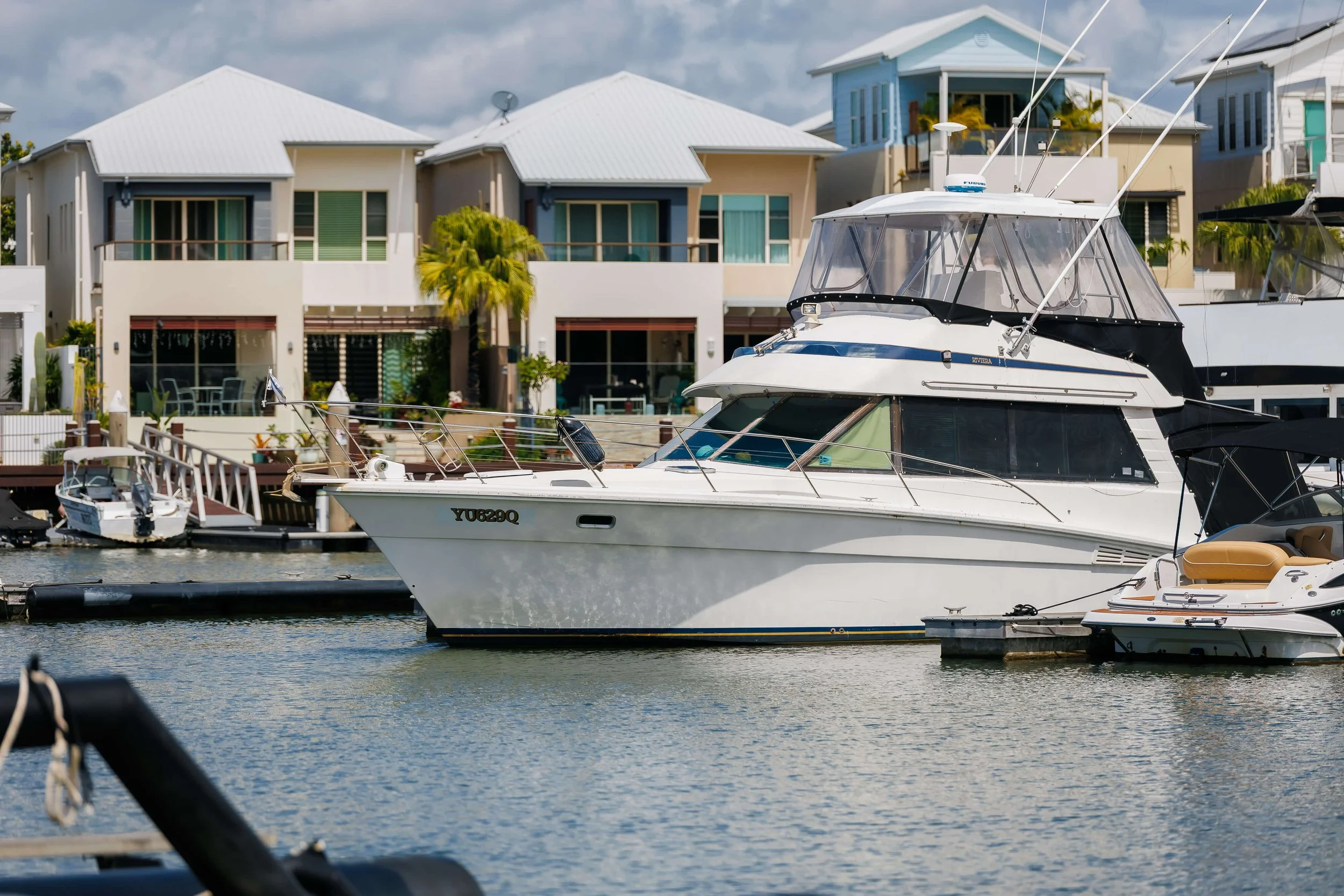 A marina with several luxury yachts docked in front of residential buildings with balconies and large windows.