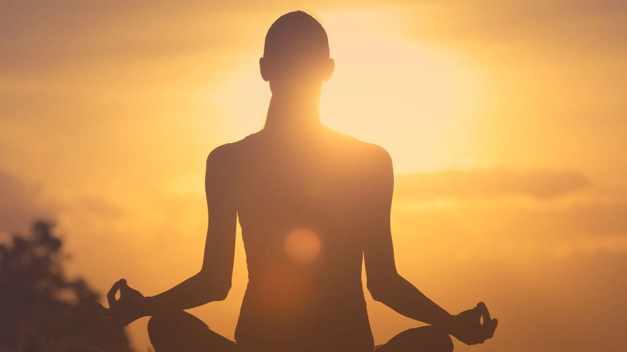 Persona haciendo yoga en postura de meditación durante el atardecer, en silhouette.