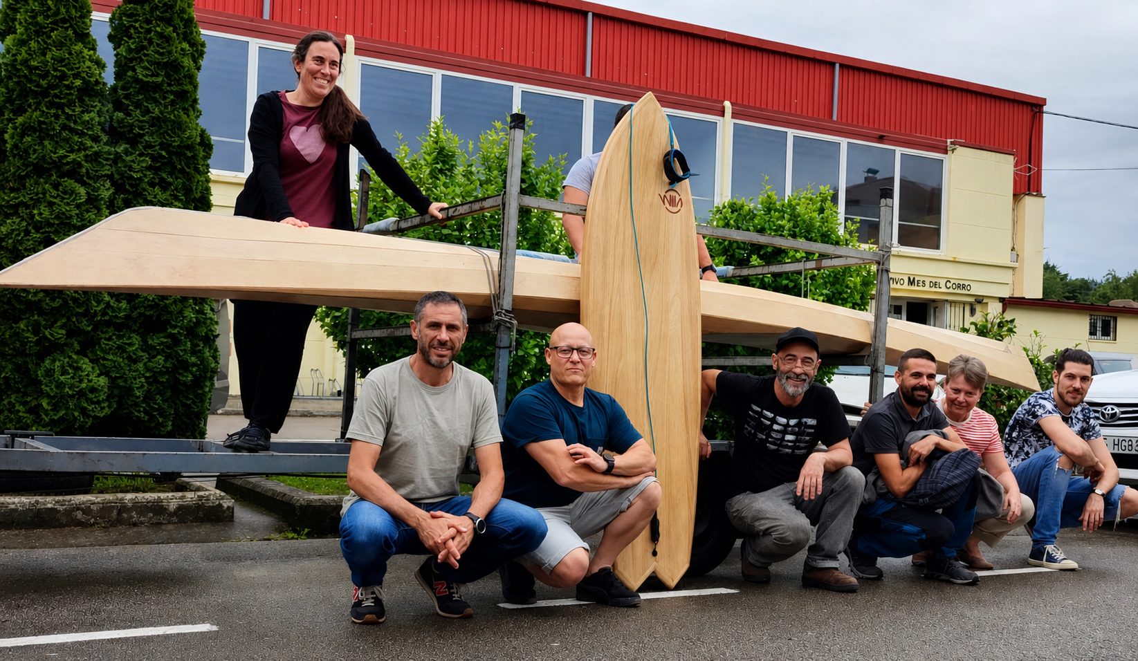 Grupo de personas con un hidroala de madera en un entorno urbano con árboles y edificios al fondo.