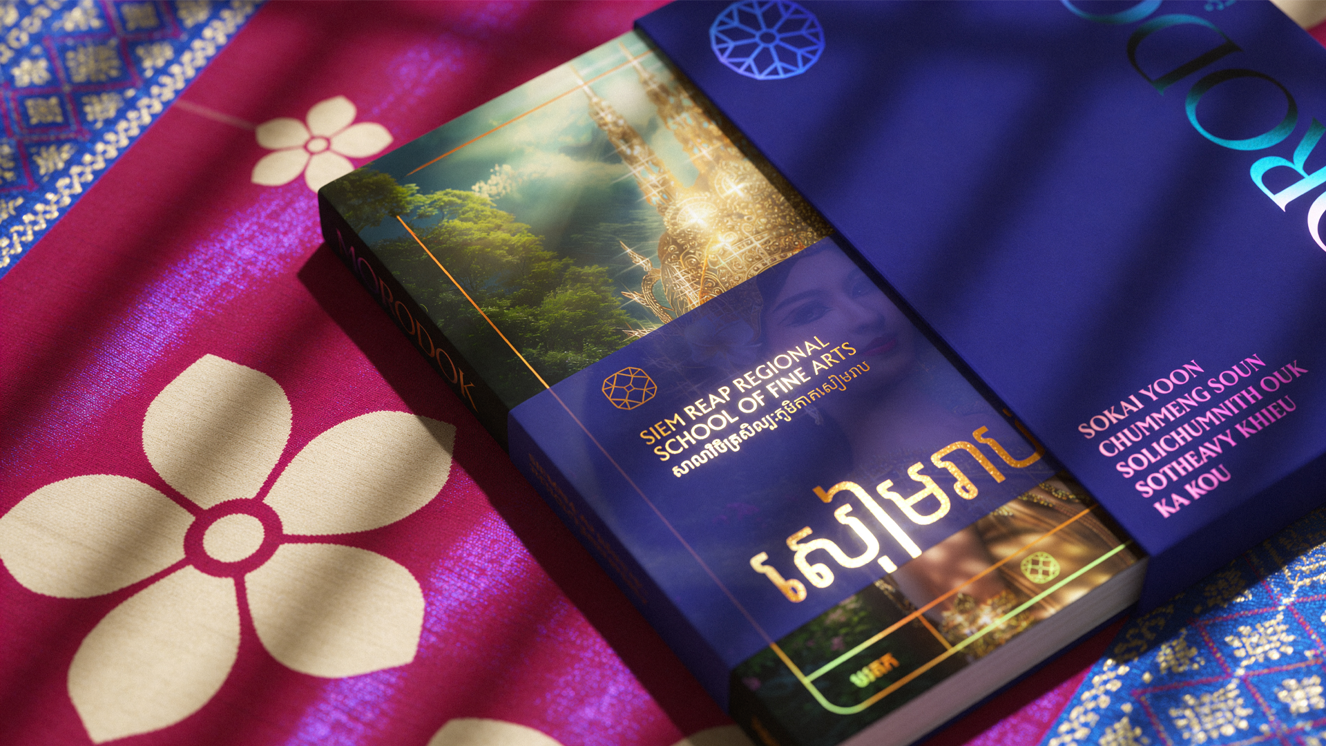 A hardcover book partially out of its blue hard case. The Book has a sleeve with the title "Siem Reap School of Fine Arts" with "Siem Reap" written in Khmer. The book sits on a magenta and blue patterned cloth of romduol flowers