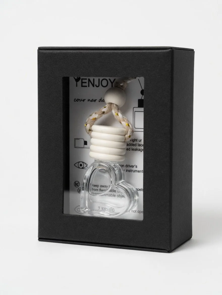 Decorative heart-shaped glass ornament with white coil, hanging from a braided rope with a bead, in a black box.