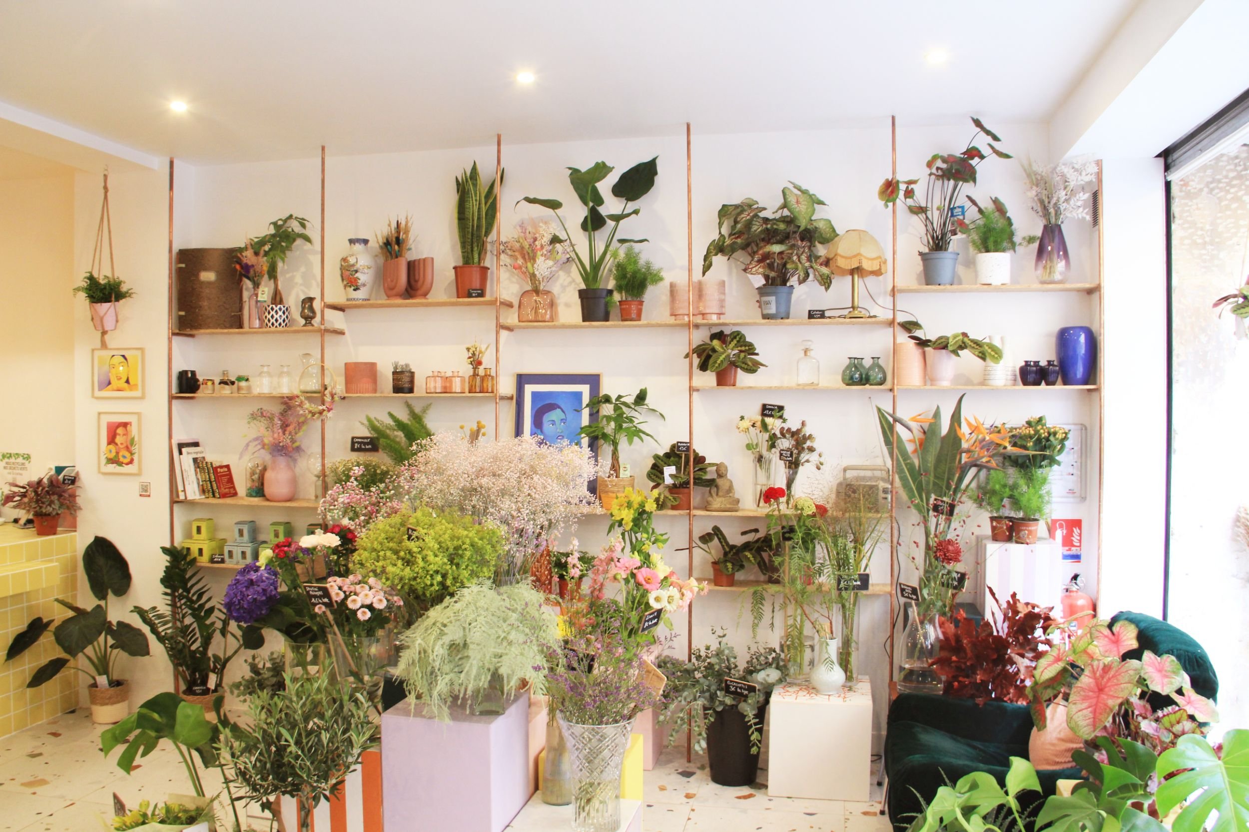 Intérieur d'une boutique de fleurs avec une bibliothèque sur mesure en fond, remplies de fleurs et décorations colorées. Au premier plans, des aménagements sur mesure pour accueillir bouquets et fleurs.
