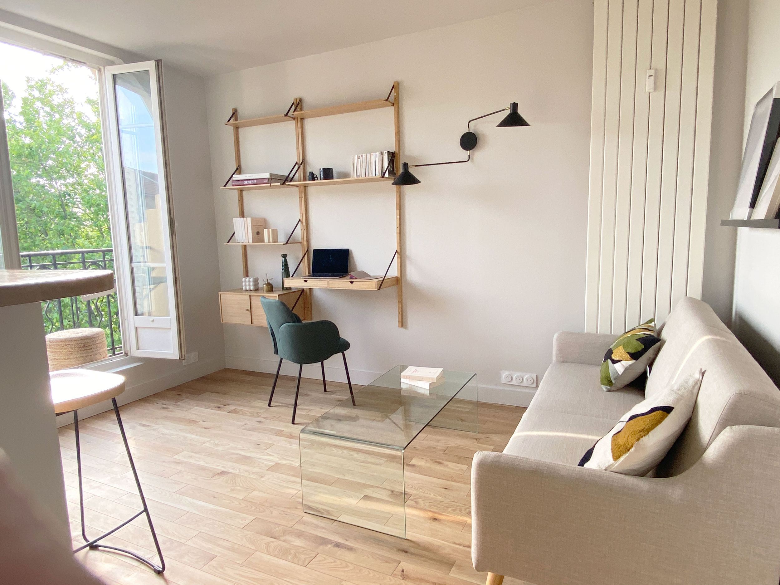 Salon clair et dégagé, avec vue sur parc extérieur. Mobilier neuf, choisi et accordé avec soin : canapé, table basse, bibliothèque avec coin bureau sur mesure