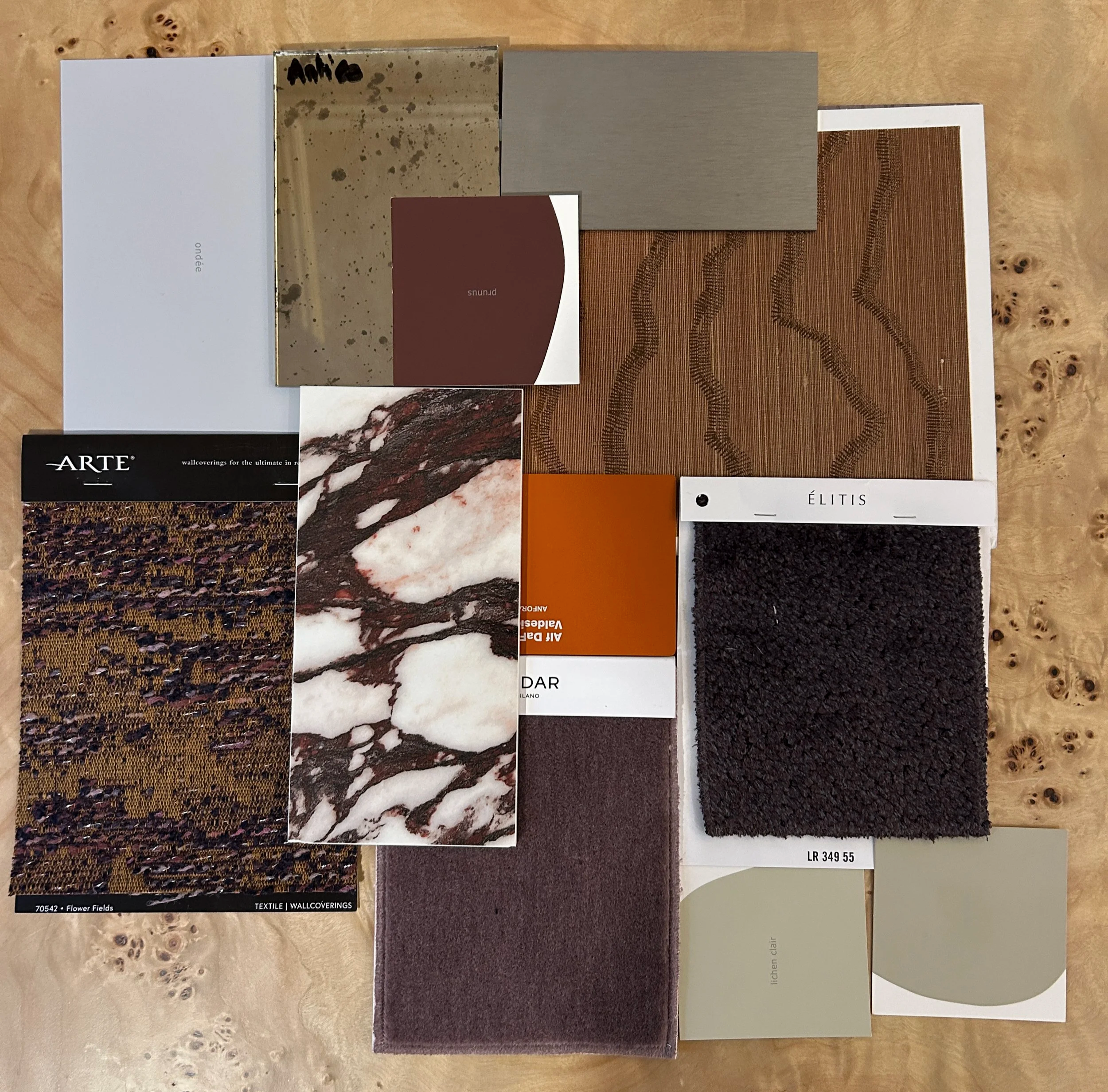 Échantillons de revêtements muraux en différents matériaux et couleurs, comprenant des textures en tissu, pierre, marbre, béton, et autres finitions utilisées pour un projet de rénovation d'un intérieur avec des agencements sur mesure.
