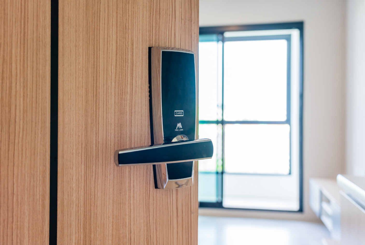 Verrou électronique avec lecteur de carte sur une porte en bois dans un intérieur lumineux.