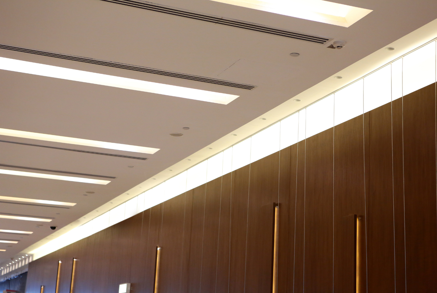 Plafond et mur en bois dans une salle moderne avec éclairage intégré.