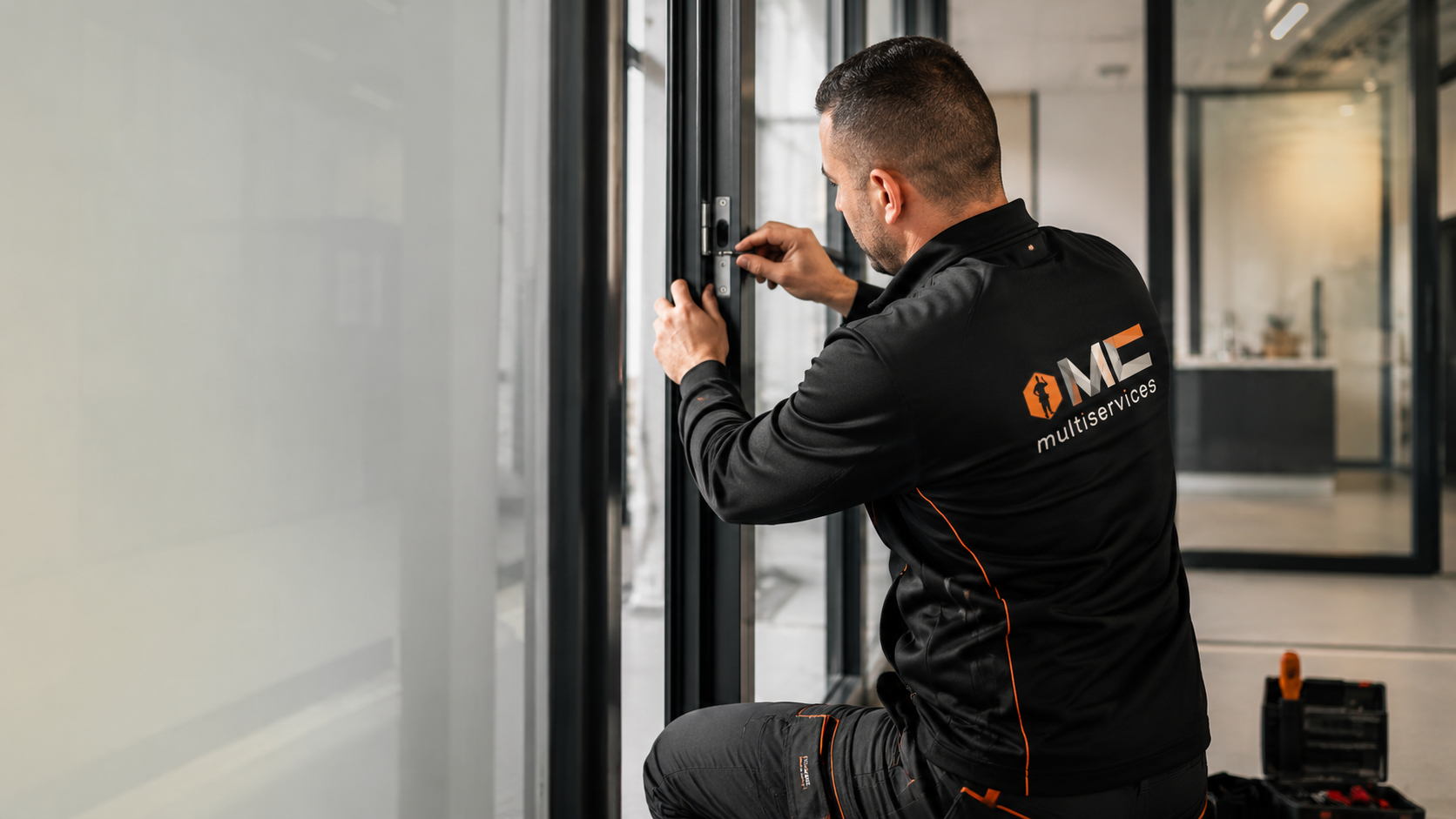 Technicien en train d'installer une serrure sur une porte en verre dans un bâtiment moderne