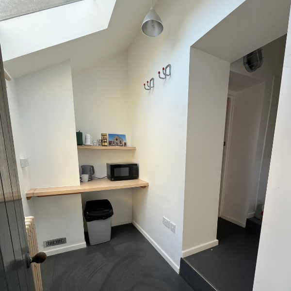 A kitchenette area with a wooden countertop, microwave, kettle, a bin and some really good sky lights.